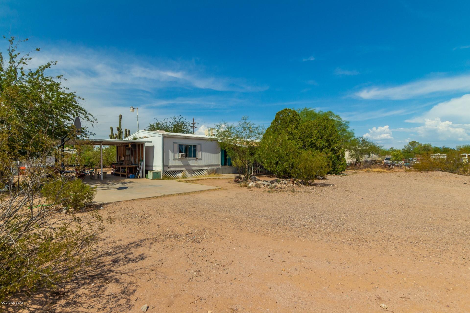 **Property is Range Priced from $85,000 to $90,000.**  Large 1.32 acres completely fenced with beautiful sunrise ,sunset and mountain views.  North/south exposure with views of Black Mountains from front of house.
Mature desert trees, and large Sahuaro make this a desert oasis.   
This property is sold ''as is'' but with some TLC it can become ''YOUR'' home.  No HOA,, and zoned SH for two dwellings.