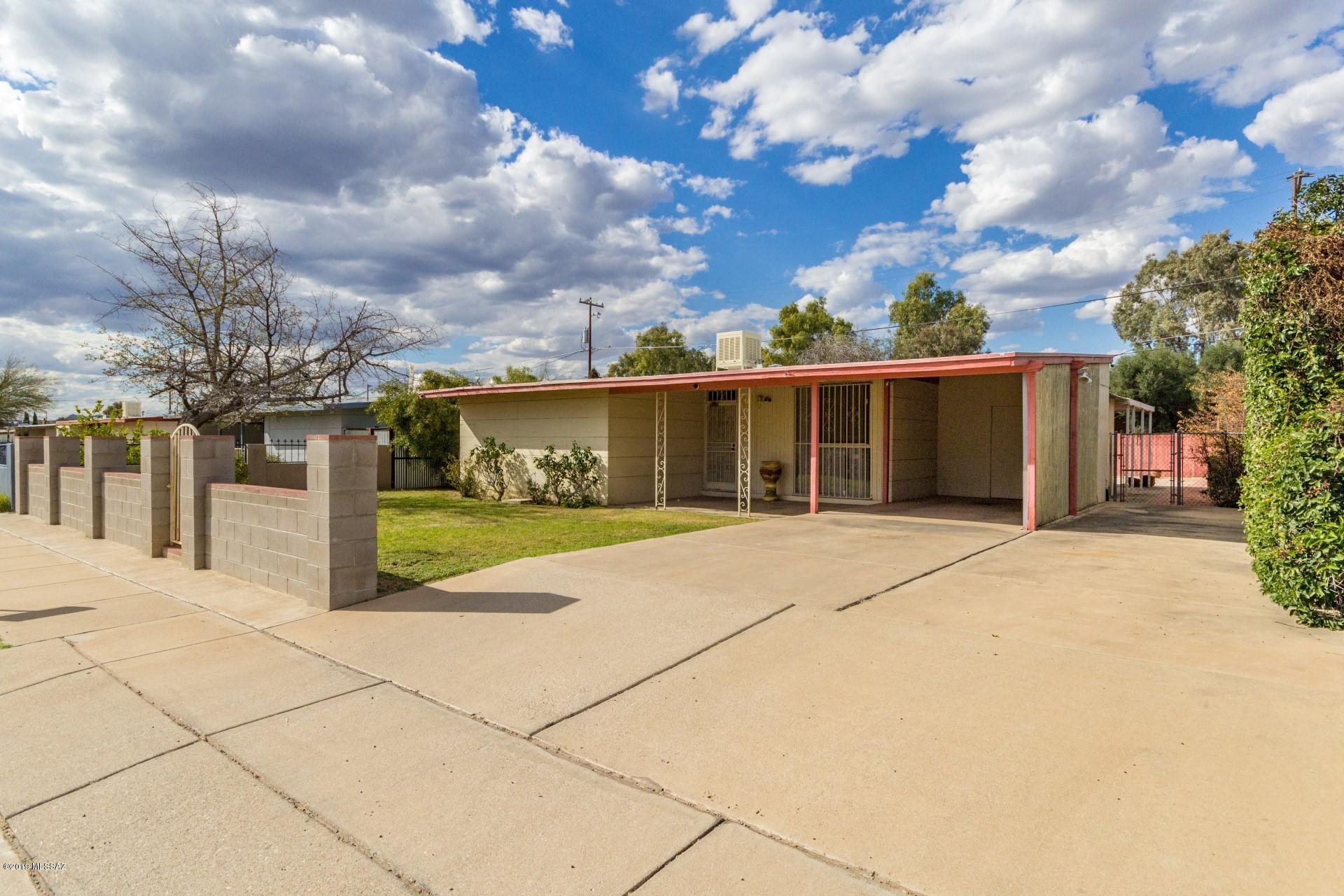 Adorable ''vintage'' home in great location!  This home boasts upgrades that create character!  Complete with a little white gate and grassy yard, the curb appeal of this home abounds!   The kitchen hosts ample cabinetry and tiled flooring.  The retro colored countertops and the pass through window add the finishing touch!  The gorgeous brick corner fireplace is great for those cool Tucson nights.  Delight in the master wood paneling walls and vintage bathrooms!  Step outside on to the covered patio and take in this great backyard. Mature fruit trees and pavered basketball court/patio provide a great place for entertaining and evening meals!  Take advantage of the brick oven and the grassy area! A storage area is convenient for your storing needs! "Retro" is IN!  This home is priced to sell!  Put it on your list to see today!