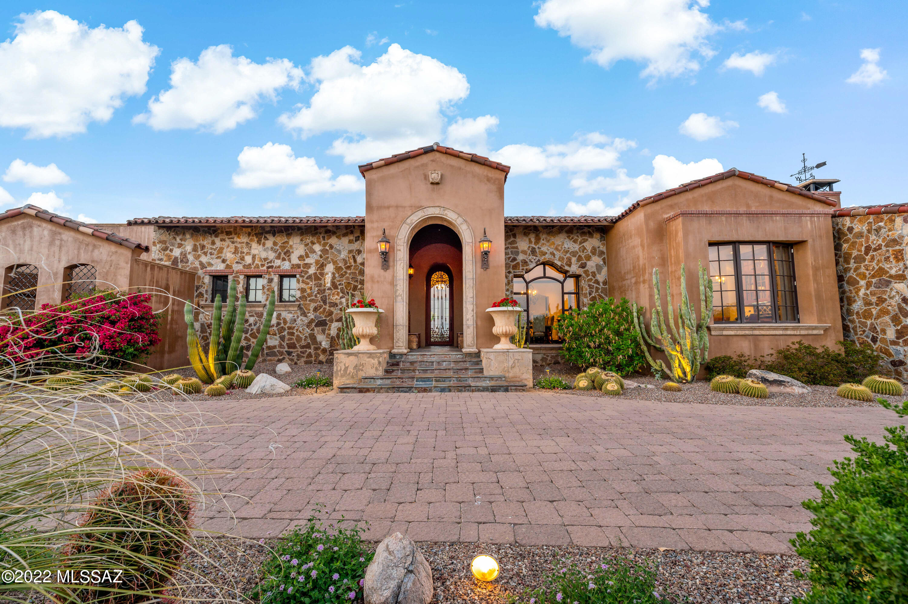 Hacienda Excepcional |  Fully-Furnished Home with Stunning, Unobstructed  Mountain Views-- Protected Infinitum. Centrally located in the coveted gated community of Stone Canyon Golf Club, this 4BR/4.5BA  residence simply dazzles with Santa Barbara-inspired architectural styling, rarely-found solid masonry construction, and a meticulously landscaped 1.97-acre lot. Masterfully designed by Ron Robinette and professionally constructed by builder, Jeff Willmeng, this one-of-a-kind property delivers an elevated living experience with an organically flowing floor plan, high ceilings, quality premium finishes throughout, an enormous living room, stunning wood beam ceilings, ebony hardwood floors, rustic slate stone flooring, and a gourmet kitchen featuring a Wolf Sub-Zero appliance package, a stainless-steel center island, handmade custom cabinetry, a breakfast nook, with an adjoining dining room. Unparalleled entertaining opportunities abound in the courtyard, which has a gorgeous elevated saltwater swimming pool, a covered veranda, exceptional nature views, an outdoor Wolf-brand BBQ, built-in big-screen TV and outdoor fireplace seating. 1BR casita displays blue Spanish tiles with plenty of room for a family stay. Tranquility and restful sleep are discovered in the primary bedroom with dual closets and a luxurious en suite. All bedrooms are generously sized with dedicated closets and en-suites, while one garage was perfectly converted to a dream-worthy man cave with built-in cabinetry (operable garage door for easy conversion). Other features: attached 3-car garage, laundry room, two fireplaces, Control-4 audio/video system throughout the home/courtyard, huge storage room off garage; extensive house and pool door alarms; active fire sprinkler and smoke alarm system; first-class community with swim, tennis, golf, and health facilities, close to shopping, restaurants, and schools.