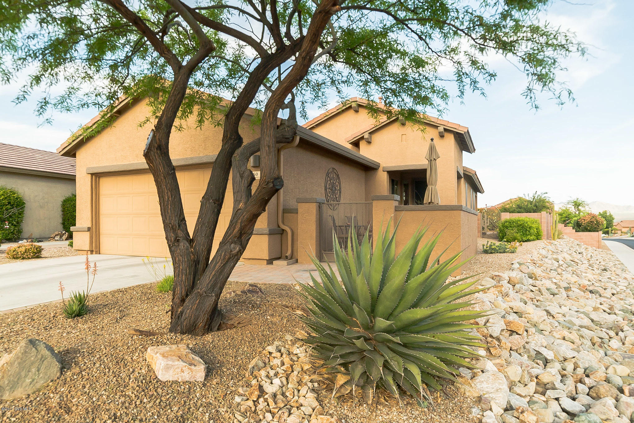 Come take a look at this wonderful home nestled on a corner lot with a mature desert mesquite tree dispatching shade on your front courtyard. Radiant light from two large plate glass windows sweep across the great room with gorgeous floor tile. The open floor plan flows nicely with a pony wall offering slight separation to the dining area which provides lovely views of the back patio. The open den gives you a place to watch your favorite show or movie plus you'll appreciate the beautiful built-in workstation and shelving to keep things organized. The brilliant kitchen features white appliances including a double door refrigerator and a gas cooktop range and the under-cabinet light fixture draws out a multitude of colors in the solid granite countertops that encircle the efficient