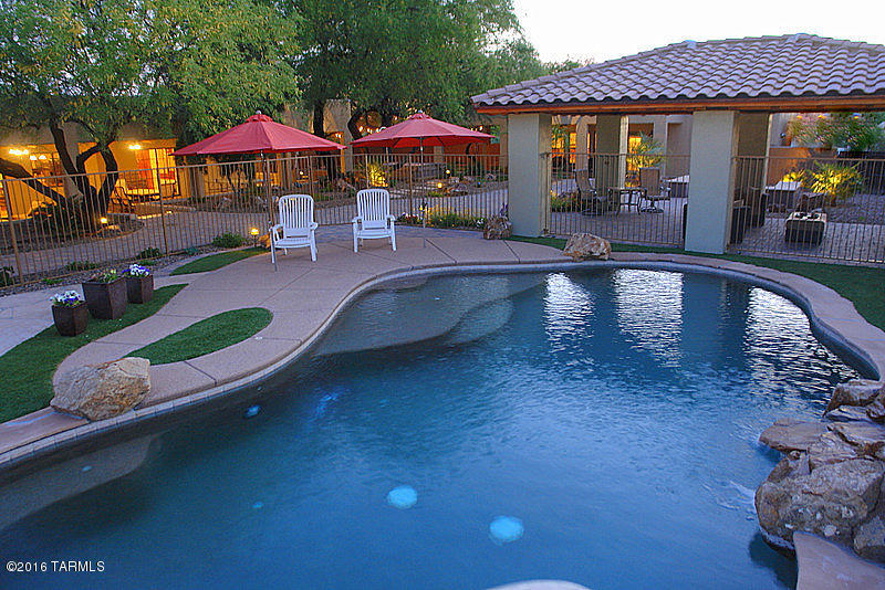 Absolutely incredible property in one of Tucson's most desirable areas! Custom built 5bd/4ba home plus 980 sqft 1ba/1ba detached guest house with separate entrance, parking, laundry, full kitchen. Main house has brand new scored concrete floors & completely remodeled master bath. Kitchen features rich Pecan cabinets & granite counters. Split bedroom plan has owner's suite opposite 4-5 guest bedrooms. 2 bedrooms have been combined to create den/gameroom - easy conversion back to 6 bedroom main house. Back yard is a stunning resort style retreat. 1400 feet of covered patio look out onto Mesquite shaded putting green, firepit, incredible Ramada with fireplace, lagoon style pool with rock waterfall & slide, plus lighted sport court. This home includes fully paid solar lease with 15 years left.