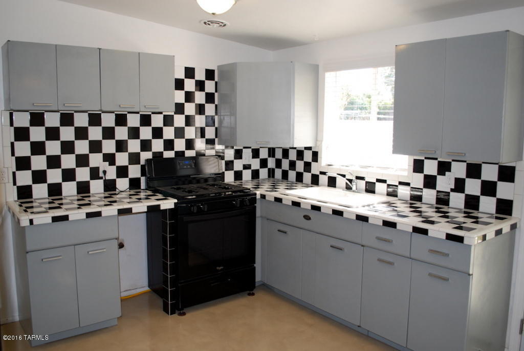 Updated Clean and Unique 3 Bedroom 1 Bath within walking distance to Flowing Wells High School. 975 SQ FT. Easy Access to I-10. New Concrete floors throughout. Retro Kitchen with aluminum cabinets, checkerboard backsplash, new gas stove and fridge. Dining area has french doors that lead to patio. Ceiling fans in all but one room. Updated Central A/C and Heat. Attached 18x10 workshop area. Full size washer/dryer Backyard has covered patio, fruit bearing orange tree, two outdoor storage units and extra wide door for alley access. This home is offered as NON-SMOKING. Pets subject to owner approval.