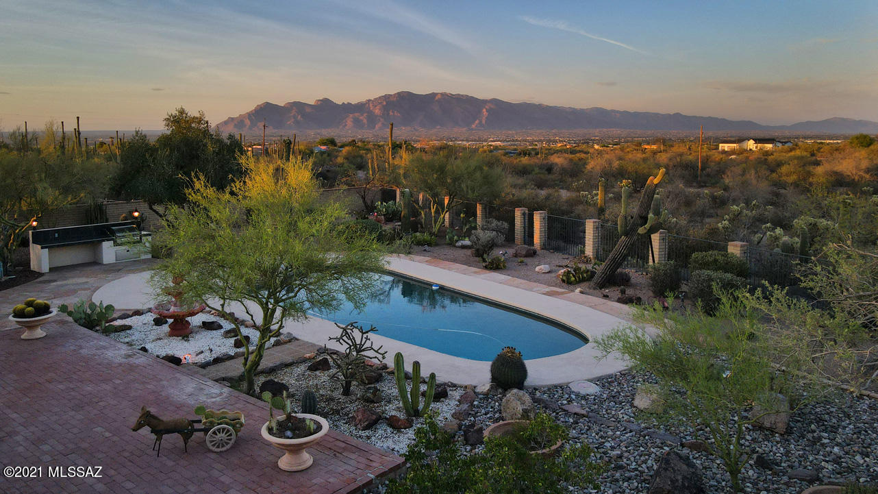 Imagine panoramic mountain views of the Catalinas, Rincons & the Tucson Mountains... mature desert flora, twinkling city lights as you entertain evenings on your patio with mesmerizing lights dancing in the pristine pool. This masonry, stucco home was built in 1974 with a guest house built in 2008. You will find exquisite leathered, stone counters in the main home, with state-of-the-art slate appliances, & luxury plank flooring! There are 2 owners suites in the main with an additional 2 bedrooms & 3 baths. The guest home has a wraparound porch, vaulted ceilings, a spacious owners suite & dual sinks with a roll in shower. This 4.12 acres is Suburban Ranch zoned & has no HOA. There are raised gardens waiting for your green thumb and a storage shed. Horses are allowed, just 20 minutes from the airport, close to shopping, restaurants & downtown with easy access to I-10. Quiet & Secluded with spectacular sunrises & pink Mountain sunsets! Welcome home