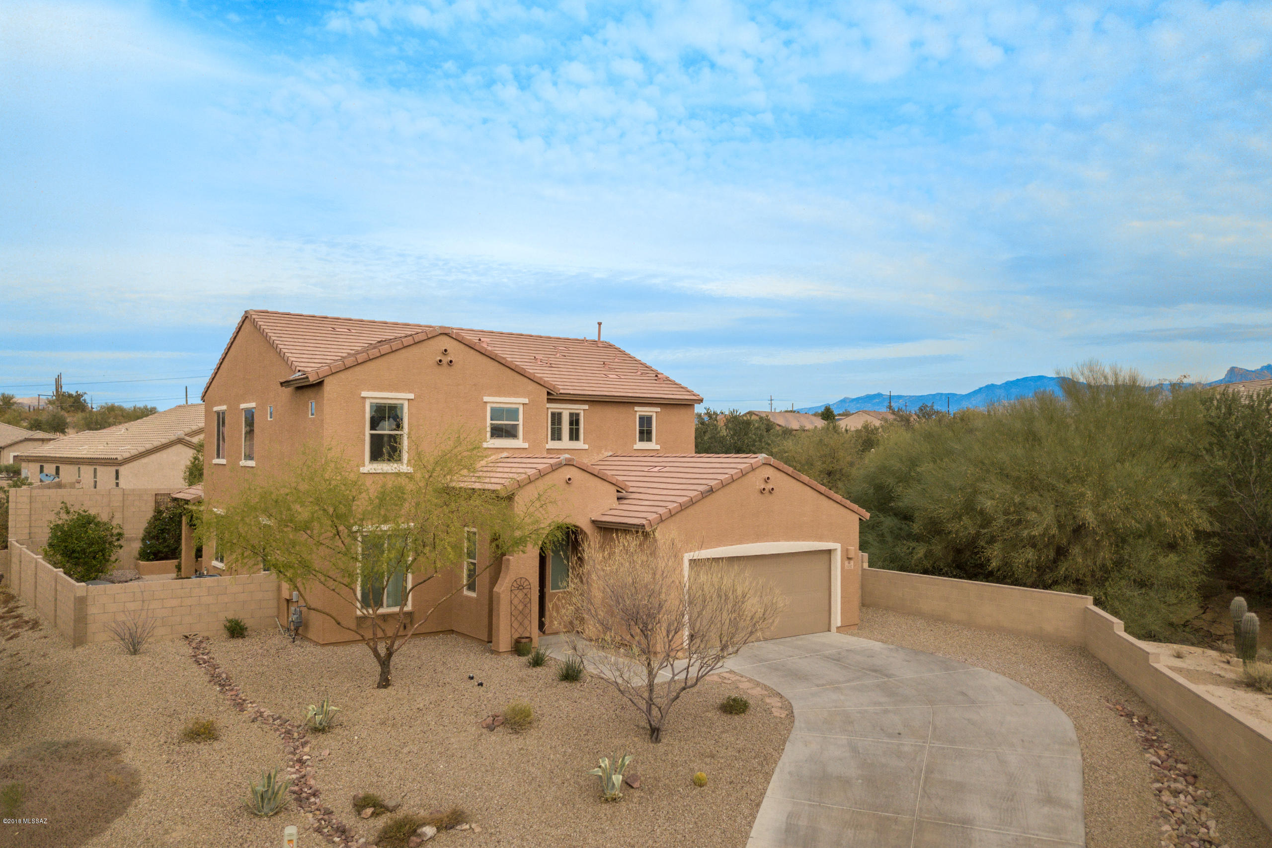 This charmer is positioned up at the top end of the cul de sac with great spacing between its only neighbor. Featuring Three-car Tandem garage, four bedrooms, three bathrooms PLUS loft area with panoramic mountain views. Bright and spacious kitchen features raised panel cabinets, granite counter tops with breakfast bar, gas stove and walk in pantry. Stainless Steel refrigerator included! One bedroom and bathroom are located downstairs, as well as a large storage closet under the stairs, great room and defined entry. The staircase has wrought iron accents. Owners suite includes separate tub and shower, double vanity, linen cabinet space and a spacious Owner's closet. Thoughtfully designed backyard includes covered patio, planters, raised beds for gardening,plentiful hardscape, citrus trees, agave's, bougainvillea, and vines. Iron topped fence by the fire-pit provides a peek into the desert without compromising privacy. A MUST SEE!