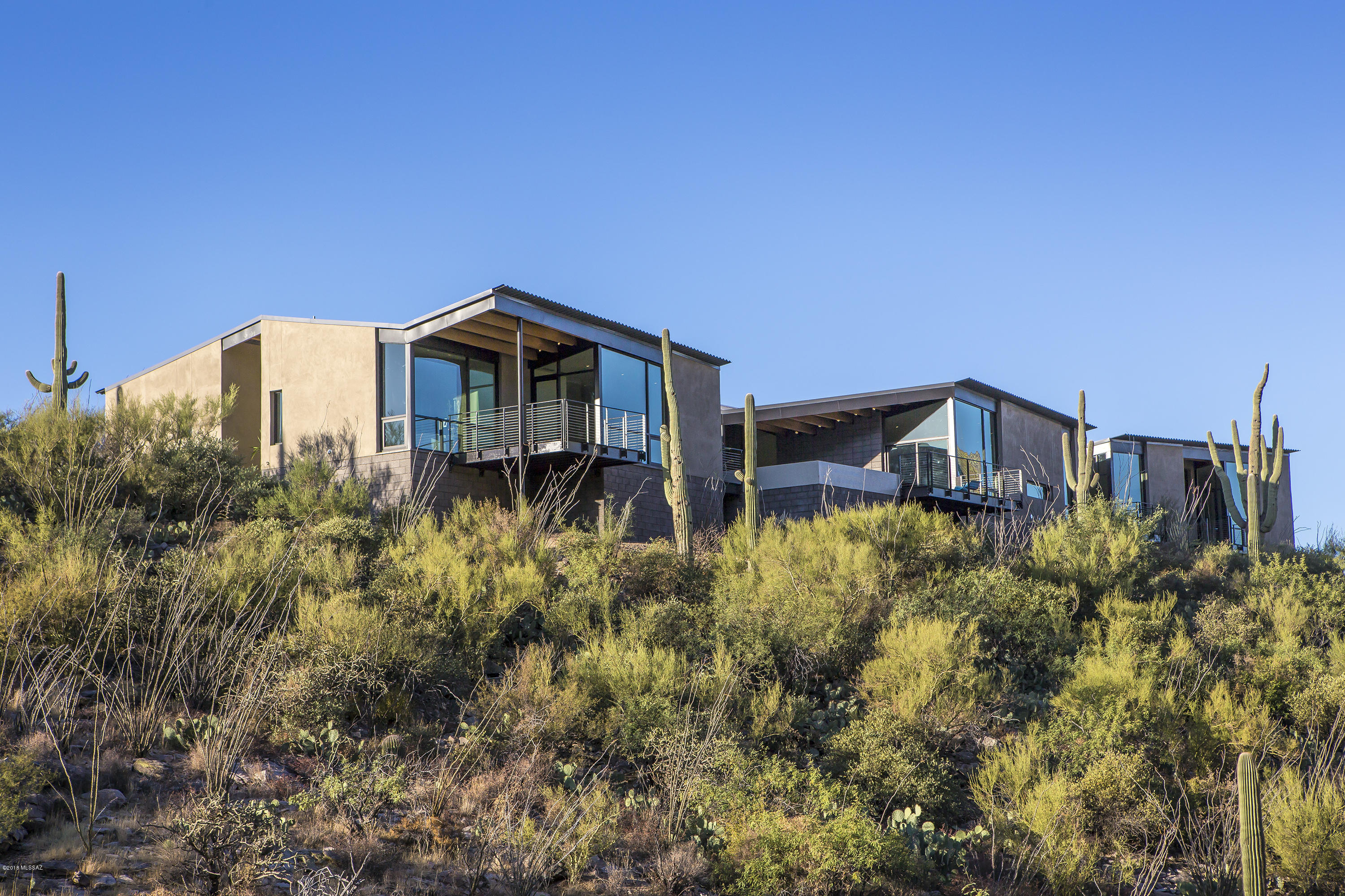 Casa de Plegado, AIA Home of the Year winner, a brand new modern home designed by Rob Paulus Architects. The unique 3.4 acre lot within the gated community of Cobblestone has amazing views, both city and mountain, and privacy, backing to the Coronado National Forest. This single level home has no steps and features a split bedroom plan with ample separate entry guest quarters, and all bedrooms are en suite. Thoughtful design features framed view windows in every room, even the hallways. Green design features include passive solar orientation, 12-inch steel framed walls with high R-value insulation, and low maintenance native landscaping. A rare opportunity to own a true contemporary at the top of this Catalina Foothills gated community.