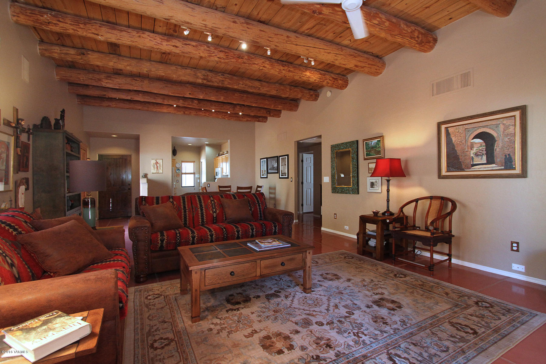 This Sante Fe style home features plank and viga beams, high ceilings, an open floor plan, & polished scored concrete floors throughout including the garage. There is a new fence on North side of house, & a new custom designed, hand made security door, new washer % dryer, and a Sante Fe style wood burning fireplace with gas.2-yr roof warranty. All rooms have ceiling fans. Custom shutters in the living room. The home was built by Chris Kemmerly, a local quality builder, see attached article in the Star. The driveway was recently redone. One bedroom is currently used as an office. Great central location on a private cul-de-sac near Trader Joes, Frys, Cross Roads, Sprouts, Costco, &easy access to the U of A and downtown. HOA maintains common area.$120 paid annually for dues. ($10 per month. ACCEPTING BACK UP OFFERS