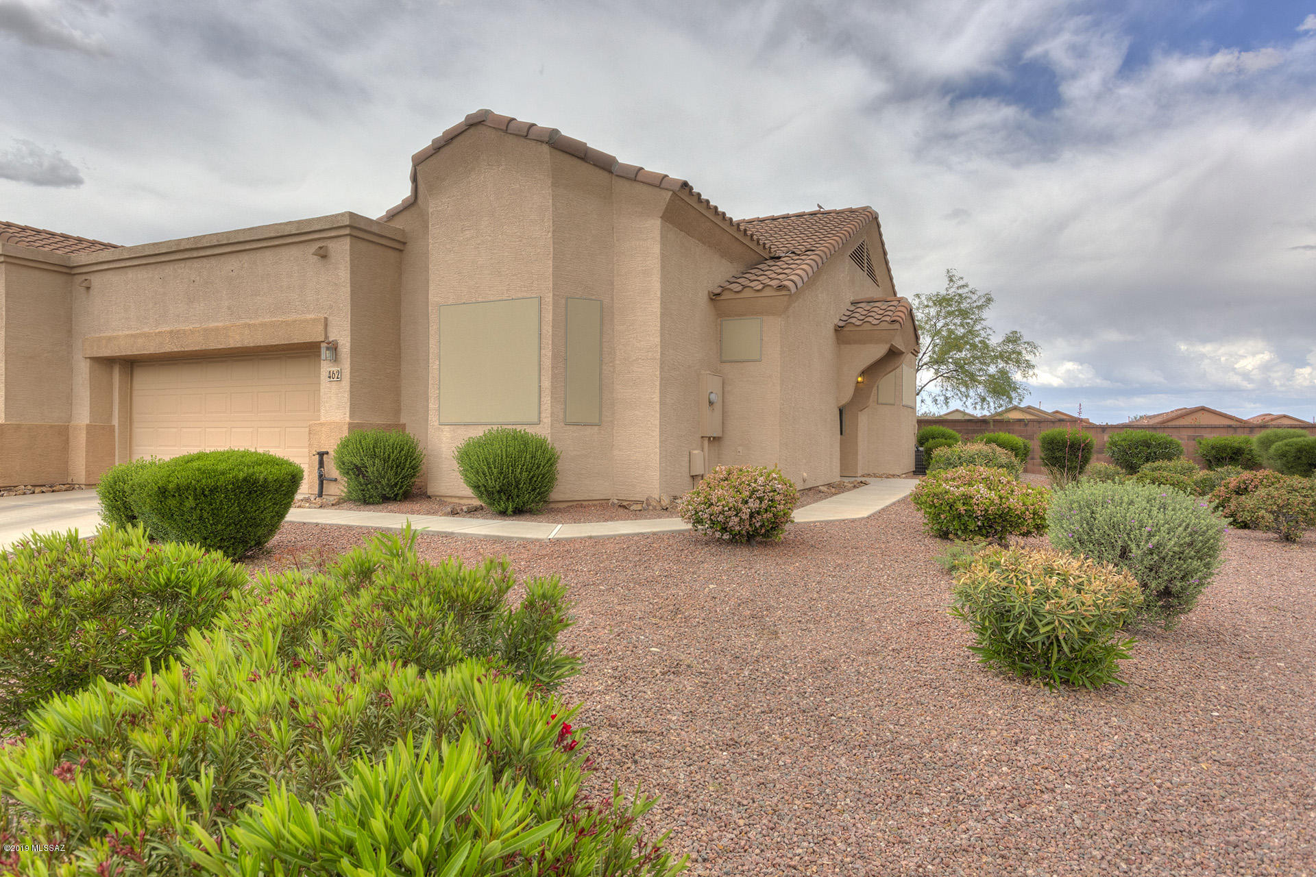 This one screams Value. Shows great and appears much larger than its 1282 sq. ft. thanks to the great room design with big windows, high vaulted ceilings, and nice neutral paint colors. A king size master BR has vaulted ceilings w/ a plant shelf. MBA has a double sink vanity, walk in closet and a large EZ care shower w/ corner seat. Front Guest BR has a walk in closet, Bright Bay window and is split for privacy from the owners. This home is the total package with all appliances including the washer and dryer. The private north facing full back patio cover is a perfect way to start your day w/ a cup of coffee or just relax reading a book in the shade during a sunny afternoon. Just down the street from the Public Library too.
Garage has a soft water loop and this one has a lot of side yard. Life is good at Las Campanas Village. It is a one of a kind HOA that is set up much like a condo, but w/ fee title. They maintain your landscaping, stucco, paint and roof. Also included is the water for your landscaping; monthly pest control; expanded basic cable TV; weekly trash and recyclable pickup; fire, hazard and liability insurance; common areas, gates and road upkeep; and they also maintain a healthy reserve fund. Flat roofs were recoated in 2018 and exterior painting is projected to start in the community this year by HOA. This is the Lifestyle You Deserve.