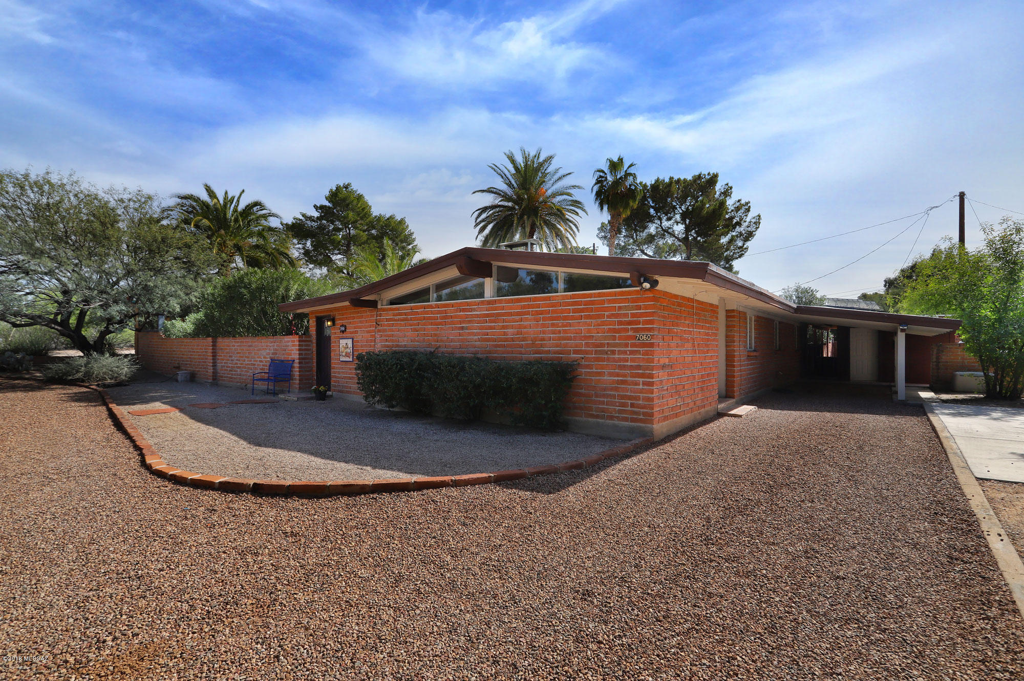 Tastefully & carefully updated Mid-Century Modern features authentic, vaulted, plank & beam ceilings & burnt adobe brick.  Living room flows into dining area & kitchen w a dramatic 3-sided burnt adobe fireplace. Living room has Clerestory windows, the family room has a wall of windows that boasts ample natural light & opens to large maintained backyard. North facing covered patio, nice sized private pool, & a gas fire-pit area just right for entertaining!  3bd/2ba home offers original cabinetry & hardware, granite counters in the kitchen & bath with a newer induction cook top, Dishwasher, oven, AC, heater, hot water heater, & electrical panel. Master Suite offers light thru a cozy, corner window with mature foliage & a secret garden, walk in closet & a secret garden, walk in closet & a newly updated subway & penny tile shower that preserves the sense of nostalgia.  Spacious laundry room with an abundance of storage & an attached carport with a workshop for your home DIYer.  Friendly Community & Convenient to shopping & dining, hospitals & entertainment. Move-In Ready, award-winning, Historic Neighborhood.