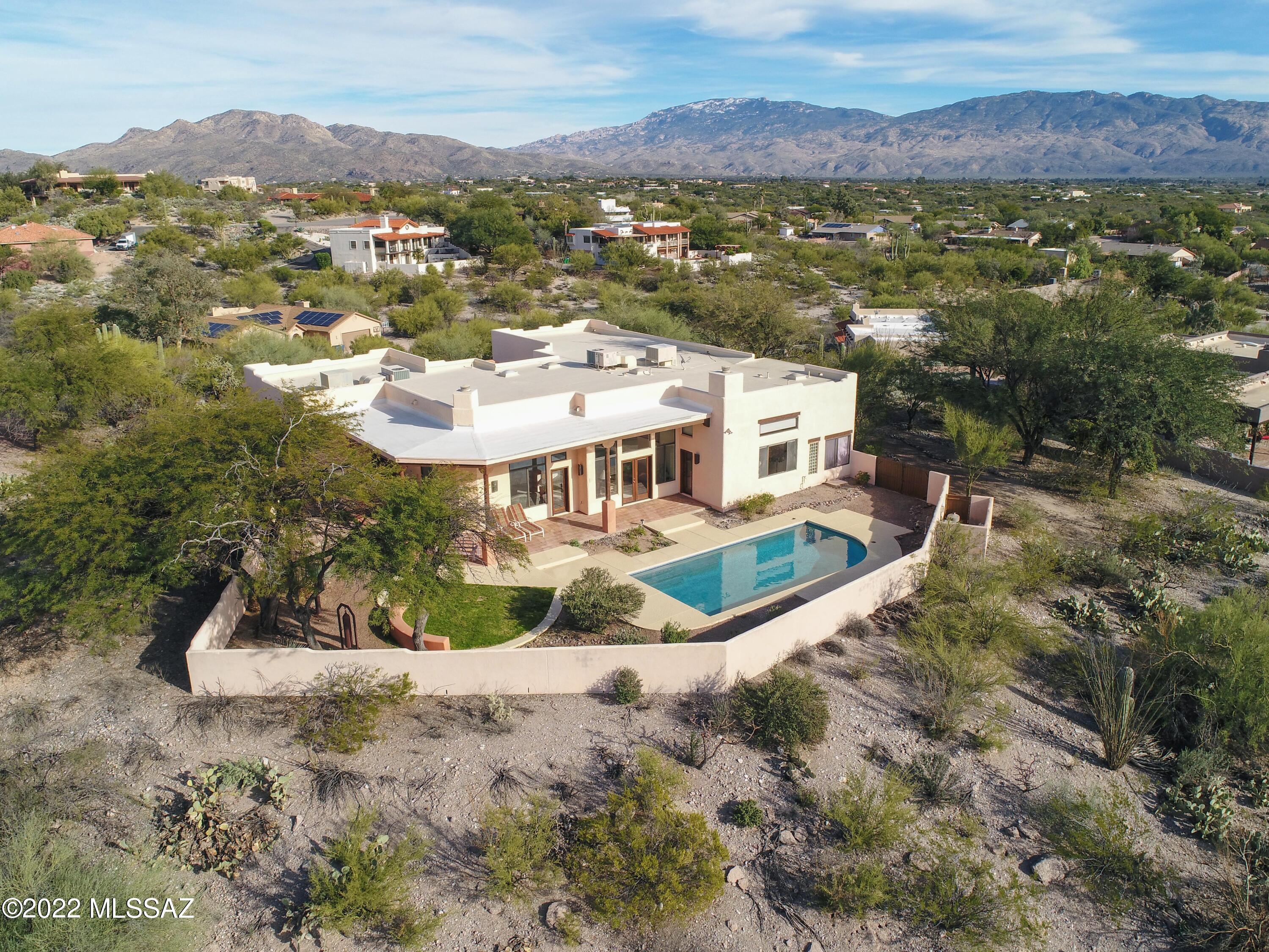 Beautiful Southwest home situated in NE Tucson is perched on an acre lot with panoramic views! This one-owner custom home welcomes you as you enter the front courtyard into a tranquil setting. The foyer leads you to the Formal Living and Dining rooms with solid wood plank ceilings & viga beams that continues into Family room with beehive fireplace overlooking the sparkling pool and endless views.  Kitchen features oak cabinets, built-in stove top, oven, microwave, built-in desk, walk-in pantry, breakfast bar & nook. The master suite on lower level has wet bar and wood fireplace. Master bath features split vanities, separate shower and jetted tub. Generous-size three guest bedrooms on main level. Two guest baths. Relax in the private backyard where you can soak in the views from covered patio or pool with in-floor cleaning system. Additional amenities include oversize 3-car garage with separate storage, Saltillo floors, Berber carpet, laundry room. Close to Arizona National golf course, Mt Lemmon, shopping, Mc Donald Park and great hiking and biking! Make this desert oasis your own!