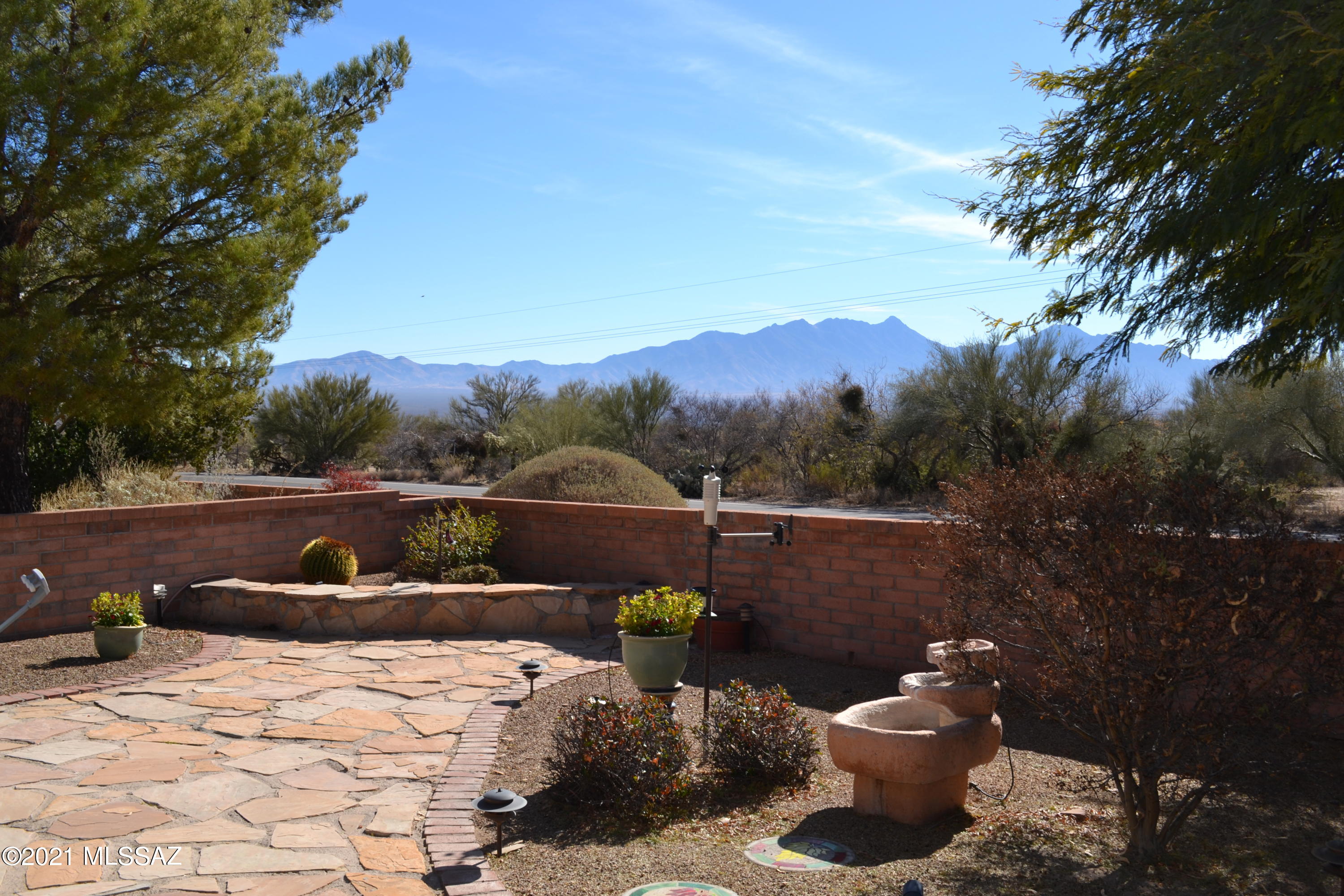 Welcome to beautiful mountain views in a quiet neighborhood. This open floorplan includes a large great room with wood flooring, a gas fireplace and large picture windows with views of the Santa Rita's. If it's outdoor entertaining or relaxing you desire, you can enjoy the covered flagstone patio, sitting area, fountain or cooking with the built-in gas barbeque. The community pool is conveniently located across the street. The kitchen features a large island for entertaining, a double convection oven, gas cooktop and a prep sink on the island. This home has two large bedrooms and a den with a Murphy bed.