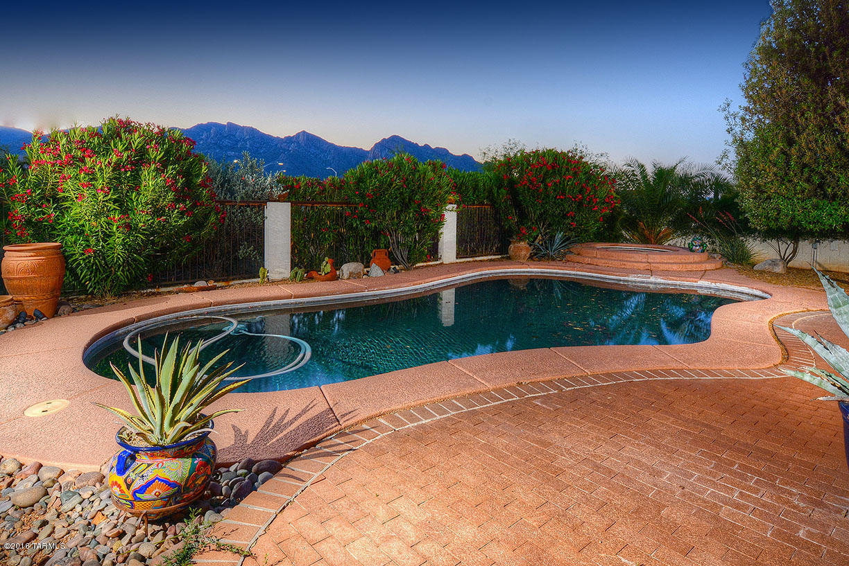 I sold this wonderful home years ago.  Since then it has been lovingly updated yet keeping the charm of a ''soft'' Santa Fe. Be entranced by unbelievable mountain views and easy access to the golf course.   Outdoor living at its best with inviting pool and spa.  Inside? Simply charming. Inviting great room, formal dining, and still a kitchen that was tastefully remodeled.  Master suite with doors to the pool and a remodeled bathroom that shows the work of a talented designer. 2 light and bright bedrooms and such a ''fun'' 2nd bathroom.  I have always loved this home as it is such a reflection of what Tucson living is all about.