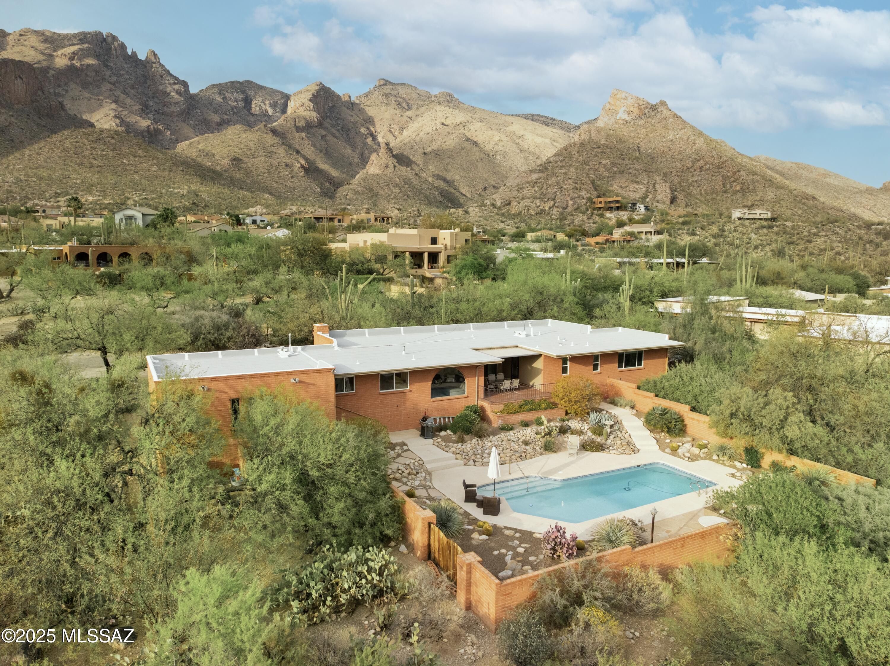 Views, views, views! Nestled in the desirable Coronado Foothills Estates, this beautifully designed home offers breathtaking panoramic views of Tucson from this hillside lot. Step inside to a bright, open floor plan filled with natural light, enhanced by arched windows that frame the stunning landscape. This home features updated tile floors throughout, a charming beehive fireplace, and a seamless indoor-outdoor flow. Outside, a covered patio overlooks a sparkling pool, surrounded by lush desert, creating a private oasis to relax and take in the views. Nearby, you'll find some of Tucson's best hiking, shopping, and dining spots. Don't miss this incredible opportunity to own a Foothills gem!