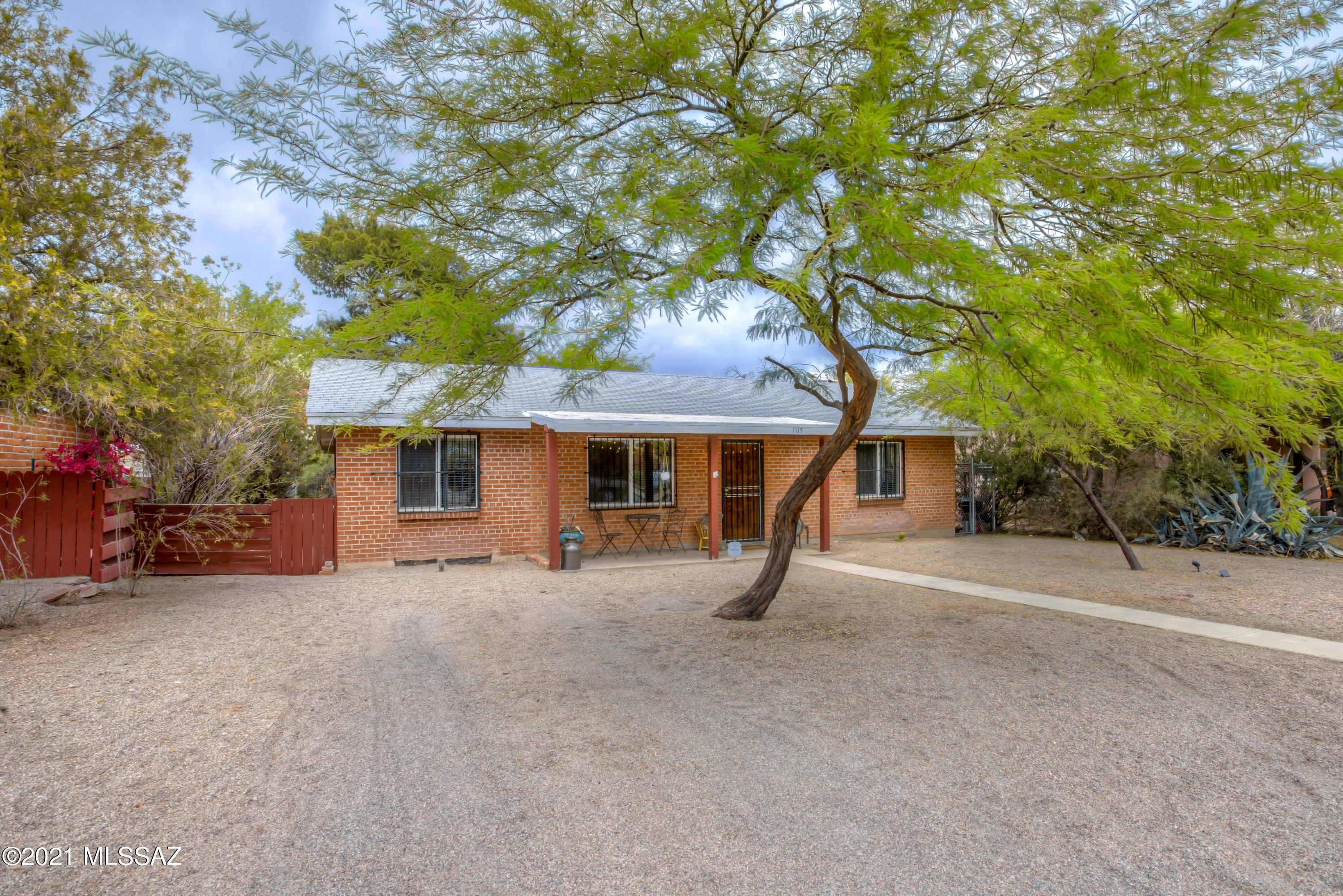 Charming 1950's brick bungalow! Home features  tile throughout, stylish updates include modern paint, accent kitchen wall-paper, updated lighting & fixtures, granite counters, SS appliances, newer windows & wood-blinds throughout, molding installed around doors & windows, newer ceiling fans installed in living room & guest BR, all appliances convey and light installed in exterior laundry room. Recently fenced-in spacious backyard w/ mountain views & mature trees is perfect for entertaining around fire pit, plenty of room for gardening, a chicken coop and more! Additional storage shed attached to carport and more off street parking available in front.  Convenient central location close to U of A, Banner UMC, Mountain Rd bike path, downtown, I-10, shopping, dining, fitness centers & more!