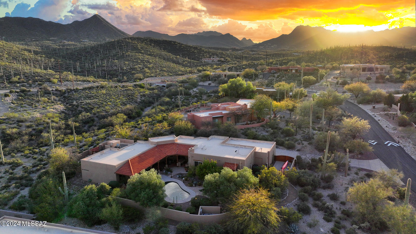 Located in a gated community on over one acre, overlooking a desert canyon, the saguaro studded Tucson Mountains, sparkling city lights and Catalina Mountains.   Once inside you will enjoy soaring ceilings, exposed wood posts and beams, and a flowing floor plan with multiple living areas. The spacious master suite is a true retreat with private access to the yard, a luxurious bath, and incredible walk-in closet.  The 2nd bedroom features an on-suite bath, bedroom No. 3 features an attached artist's studio with access to a private side yard and roof top observation deck.  The rear yard features more specimen cactus, wrap around covered patio, a beautiful pool, BBQ area, multiple seating areas, and city views.