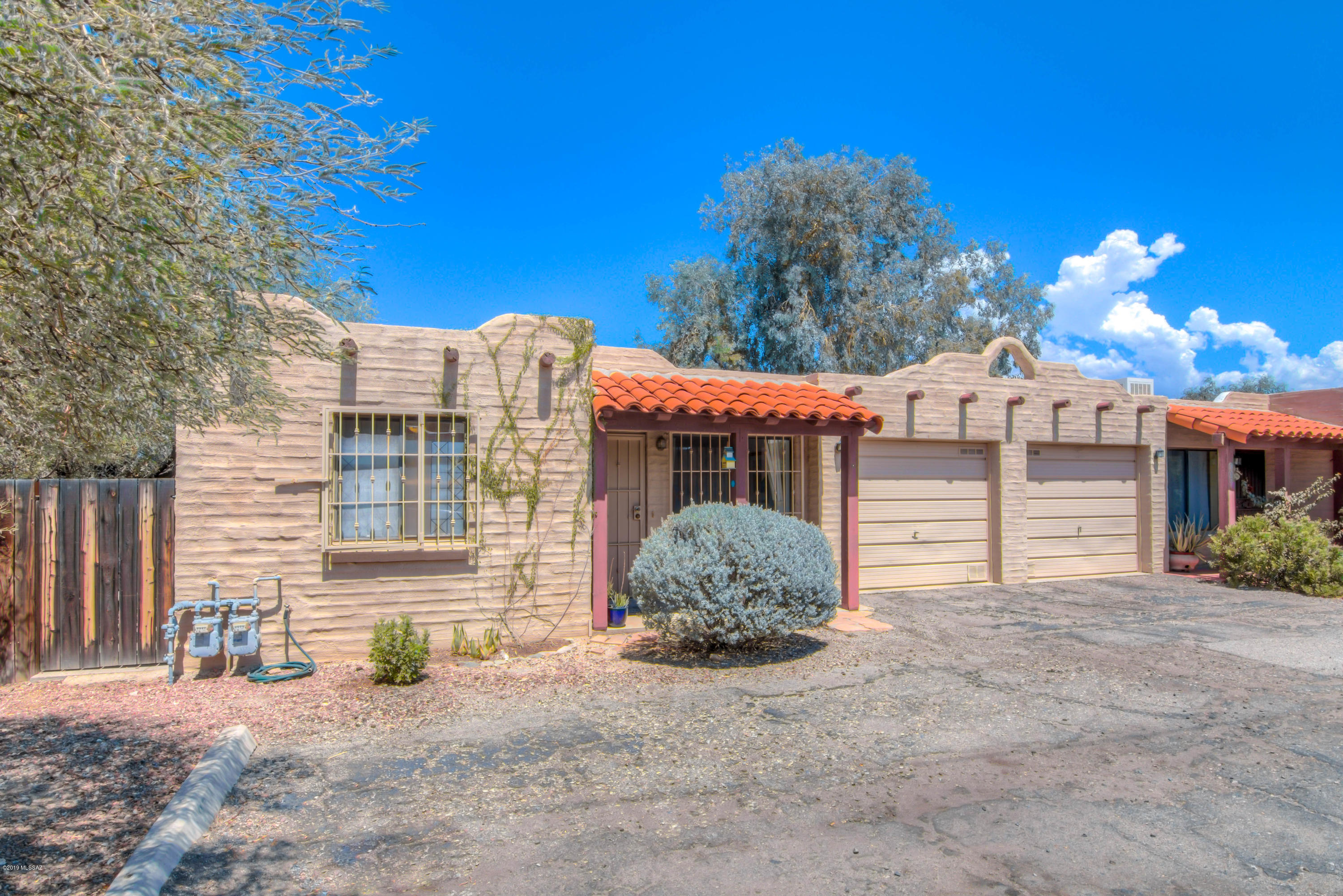 Rarely available Santa Fe style condo townhome in Fort Mesquite, a small community of 16 homes.  Conveniently located with quick access to shopping, dining, UA, and a short drive to Trader Joe's and the Rillito River Park.  The HOA covers the roof, water, sewer, trash pickup, street maintenance, and the exterior building maintenance. This 2 bedroom, 1 full bathroom townhome also has a single car garage (with room for storage) and a private backyard with a beautiful brick patio.  Move-in ready with all appliances included and a one-year home warranty.  Owner occupied only.