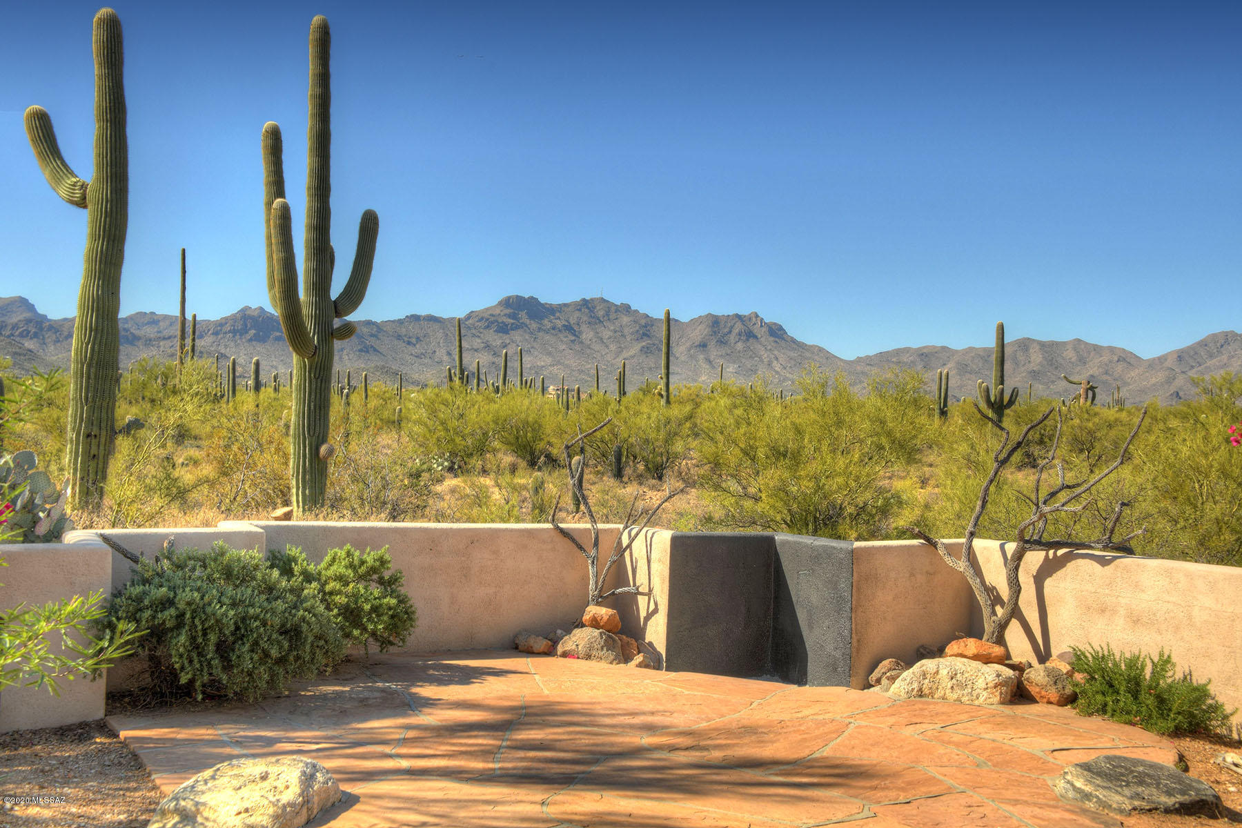This custom built retreat is nestled on 3.31 acres w/ beautiful saguaro studded desert & mountain views! Located close to amenities, I-10 access, & convenient shopping, this property is truly a private oasis. Home boasts 3 bed/3 bath split bedroom plan + den/office, large open family room w/ soaring wood plank ceilings, cozy fireplace, & large picture windows to take in views. Additional formal living and dining room create a perfect space for entertaining. Large kit w/ LG SS appliances, granite countertops, tile backsplash, built-in desk & bookcases, and breakfast nook. Retreat to the spacious master suite w/ spa-like bath, walk-in travertine shower, jetted tub, dual vanities, & 2 walk-in closets. Den adjacent to the master is perfect for home office or exercise room. Neutral travertine floors flow throughout the kitchen, family room, bathrooms & laundry room w/ engineered wood flooring in the remaining living spaces. Two generous guest bedrooms and 2 guest hall baths complete the floorplan. Enjoy the spectacular indoor/outdoor living from the large front courtyard flagstone patio to take in the Tucson Mountain views or relax in the serene natural desert setting on the expansive covered backyard patio.