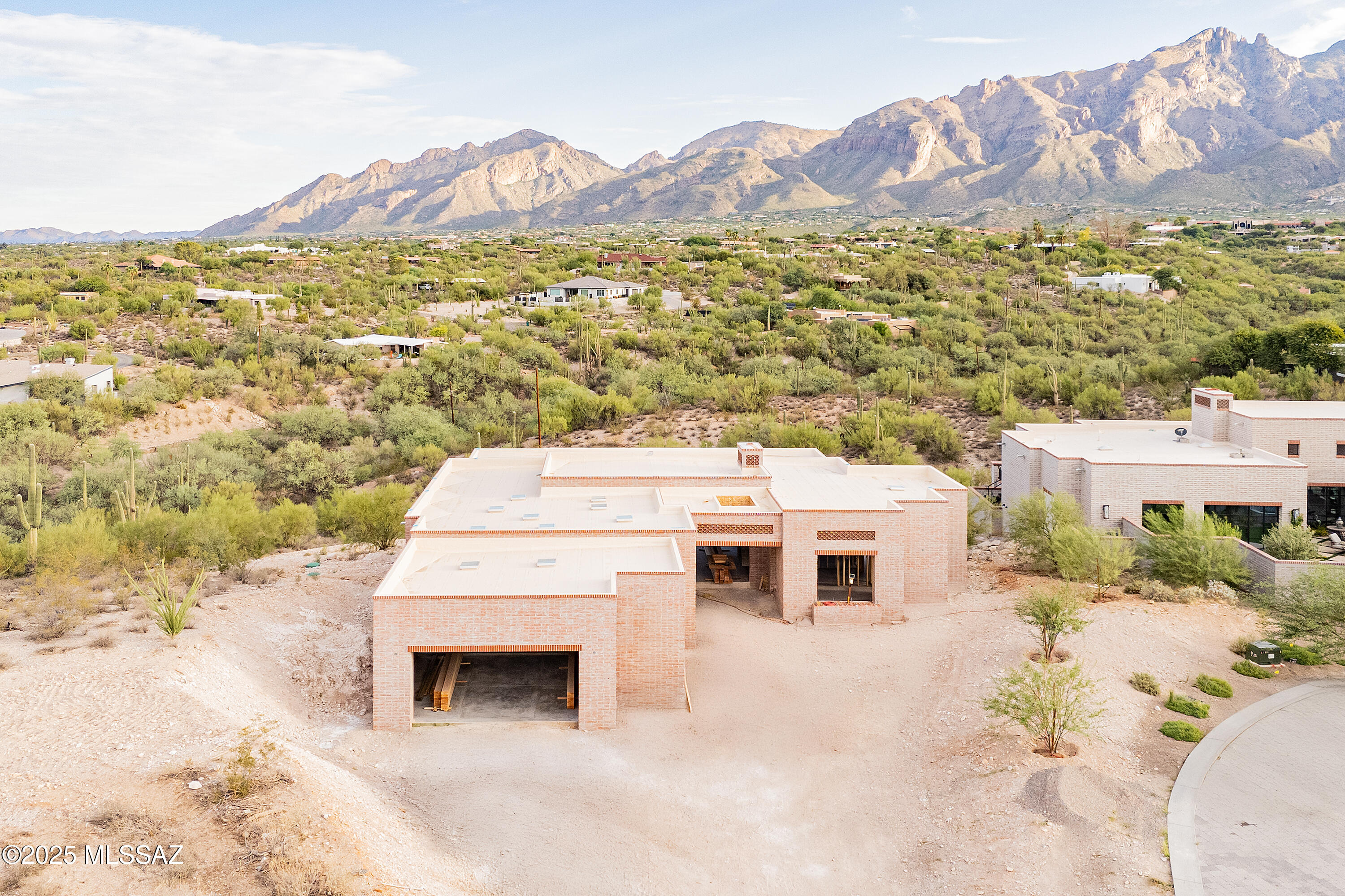 This custom-built 3,220 sq. ft. home is more than a style. Contemporary desert vernacular is an architectural language grounded in place, according to local architectural historian R. Brooks Jeffery, respecting the delicate Sonoran Desert environment, and incorporating time-honored design principles with contemporary interpretations that reflect the cultural characteristics unique to Tucson. Situated on 2.17 acres at the end of a quiet cul-de-sac in the gated Quintana in the Catalina Foothills, this residence offers unmatched city and mountain views and a level of construction quality rarely seen in today's new builds.

Designed by renowned architect Michael Franks and brought to life by La Quinta Building Company, this 3-bedroom, 2 ½-bath home is being built to endure featuring masonry construction with mortar-washed brick details and will be completed with steel casement windows and doors with dual-glazed high-efficiency glass.

Inside, the finished home's spacious great room will showcase walls of glass, a beamed ceiling, and a carved limestone fireplace, seamlessly blending indoor living with the surrounding desert landscape. Scored, integral-color concrete floors will flow throughout the home, complemented by custom alder wood and glass cabinetry and 8-foot solid wood interior doors, every detail carefully chosen to elevate the home beyond standard finishes.

The gourmet kitchen will feature a generous center island, natural quartzite countertops, and a premium appliance suite including Sub-Zero, Wolf, and Cove.

This home offers two primary suites, each with spa-like en-suites, which will feature quartzite tub decks, custom limestone tile and glass shower enclosures, and custom-designed walk-in closets with built-in organization.

Additional features will include a fully integrated audio, visual, and security system, state-of-the-art mechanical systems and motorized shades in private areas. Room for a spool.

Outdoors, a brick driveway and courtyard entry, hand-forged wrought iron gates and railings, and professionally designed hardscape and landscape will create a striking first impression. The expansive rear porch captures panoramic mountain views.

This single-level home exemplifies architectural integrity and enduring quality, designed as an extension of its natural surroundings creating harmony between architecture and nature. Located just minutes from premier golf courses, country clubs, and world-class dining and shopping. Scheduled for completion in 2026.
