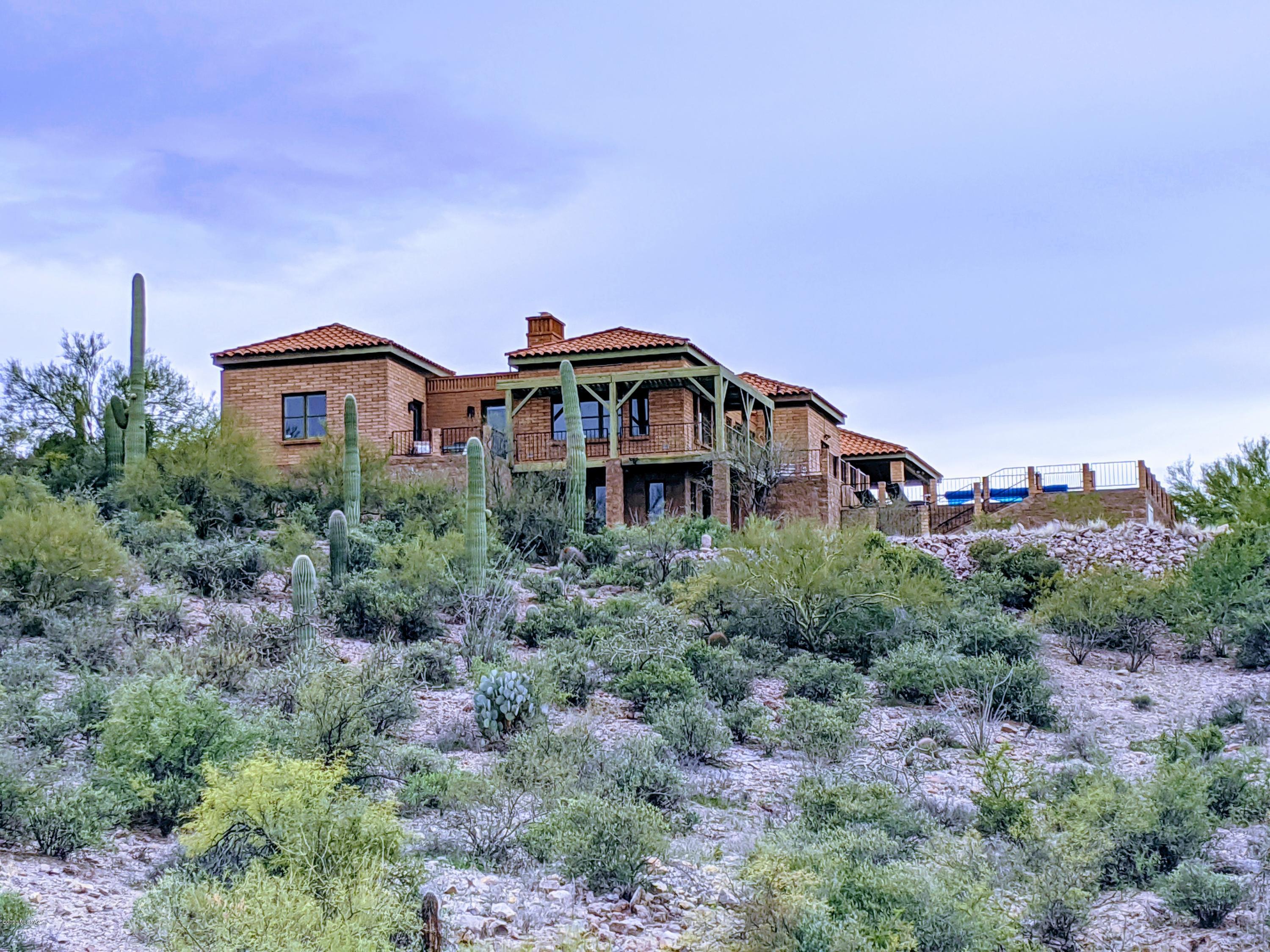 Enjoy stunning 360degree views perched on a 3.3ac peak. Relax in the pool or hot tub while you watch the sunset over Gates Pass to the west and the twinkling Tucson lights to the east. Entertain guests on the wrap around balcony, front patio, pool deck or in the courtyard. Saguaros & prickly pear surround this classic brick home providing peace and privacy. When you decide to come inside, unwind in the great room, gaze at the showpiece double-sided fireplace, and see the moonrise over the city. Two bedrooms, updated master bath and 2nd full bath await on the main floor. Invite loved ones to stay in the 3rd bedroom below the main house with full bath & separate entrance or rent the suite; no HOA! Perfectly located just 10 minutes from downtown and I-10 and steps from the Tucson Mountains.