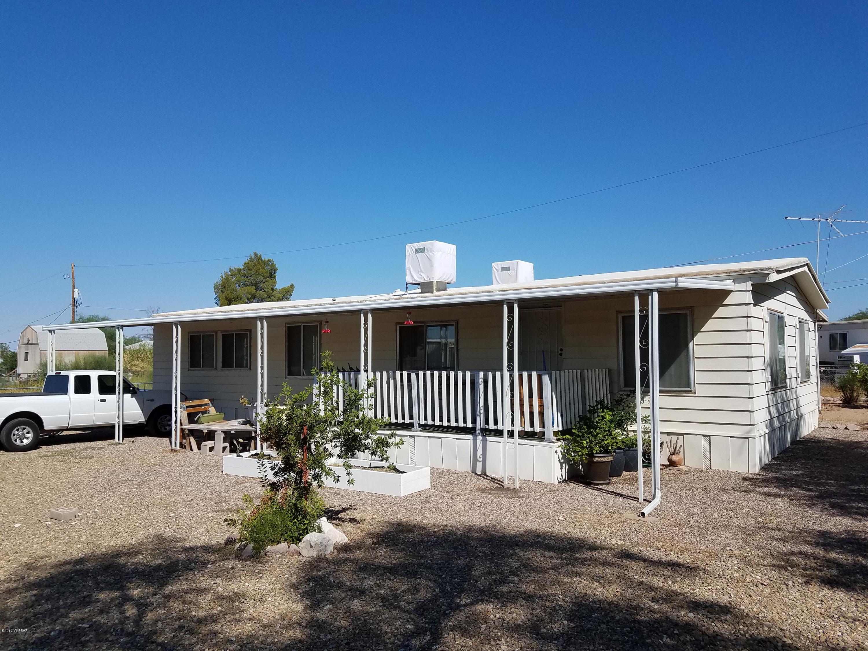 Well maintained, move in ready 2 BR 2 bath double-wide manufactured home on good sized fully fenced lot. Upgraded with central A/C, membrane roof, all aluminum dual pane windows, updated electrical, 15 X 21 garage with auto door opener & work bench, front and rear awnings & decks, several citrus trees, and 2 large gates. Large living room with beamed ceiling. Large semi-formal dining room with lots of built-ins. Kitchen has gas cooktop and double oven and breakfast bar. Washer, dryer, and refrigerator are included. Water heater is 3 years old. Master bath has separate shower and garden tub. Connected to city water, SW natural gas, and county sewer. Close to public neighborhood park with  ramada, picnic tables, playground, parking, and basketball court.