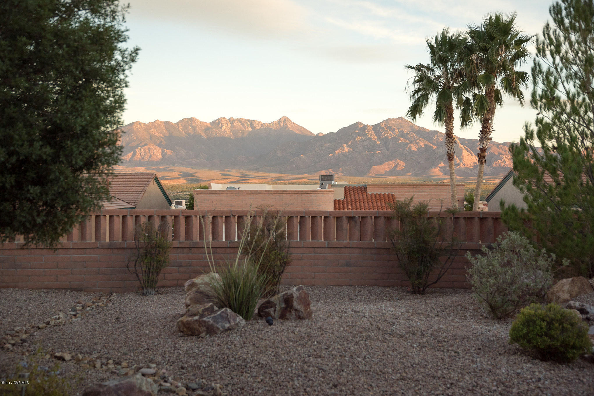 Pride of ownership abounds as you approach this beautiful home with crisp desert shrubbery immersed within decorative rock and brought to life by landscape lighting. Pass through the block archtop gateway to enter this home's living room featuring colorful custom paint, backyard viewing windows and cathedral ceilings for an exceptional open and airy feeling. The traditional dining room is wrapped in large opening windows to create a cool evening breeze while the adjacent eat-in kitchen nook is perfect for lighter meals. The efficient kitchen has a handy walk-up serving bar, brilliant hardwood cabinetry, tile backsplash and quartz countertops. And, the adjacent family room has a built-in desk for computer work. This home was 2 complete master suites for extra room and privacy. Take  time to relax and enjoy the backyard with its expansive covered patio, a flowing paver extension, boulder and rock gardens and unobstructed views of the Santa Rita Mountains!
