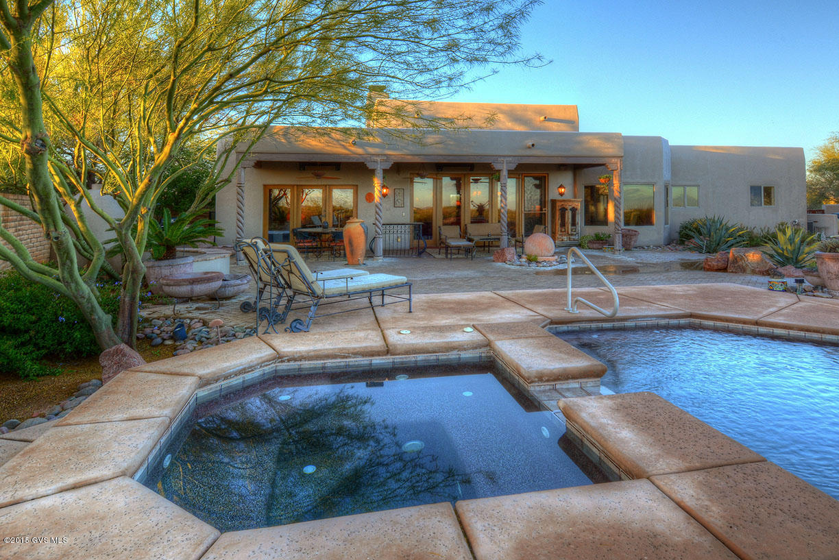 Start each day in your private front courtyard and watch the sunrise as it burns the early morning dew off the freshly painted stucco finish of this one of a kind Spanish Colonial haven. The essence of southwest living featuring dark stained saltillo tile floors and peeled viga beams which accentuate the cathedral height ceilings and clerestory windows. A floor to ceiling double sided kiva fireplace is the center piece of this warm living room and combines beautifully with the spanish floor tile to offer a true south of the border flare. The kitchen has a rich, warm ambiance with new gorgeous granite countertops, luscious hickory cabinetry, professional grade gas cooktop and hood, top quality double ovens and side by side refrigerator plus a center prep island. Enter through double  french doors to an incredible office area with ornate custom cabinetry complete with murphy bed. Retreat to your private master bedroom with its gas log fireplace and lavish bathroom suite featuring a large glass walk-in shower with dual shower heads, separate his and hers vanities separated by a built-in makeup station and a luxurious corner soaking tub with a glass block window. One of a kind private outdoor setting complete with gas kiva fireplace and trickling waterfall - enjoy a refreshing dip in the lap pool or a warm soak in your hot tub. This home is nestled into the desert landscape with miles of natural desert and majestic views of the Rincon and Santa Catalina Mountains as a backdrop. Ahhhh - a dream come true!