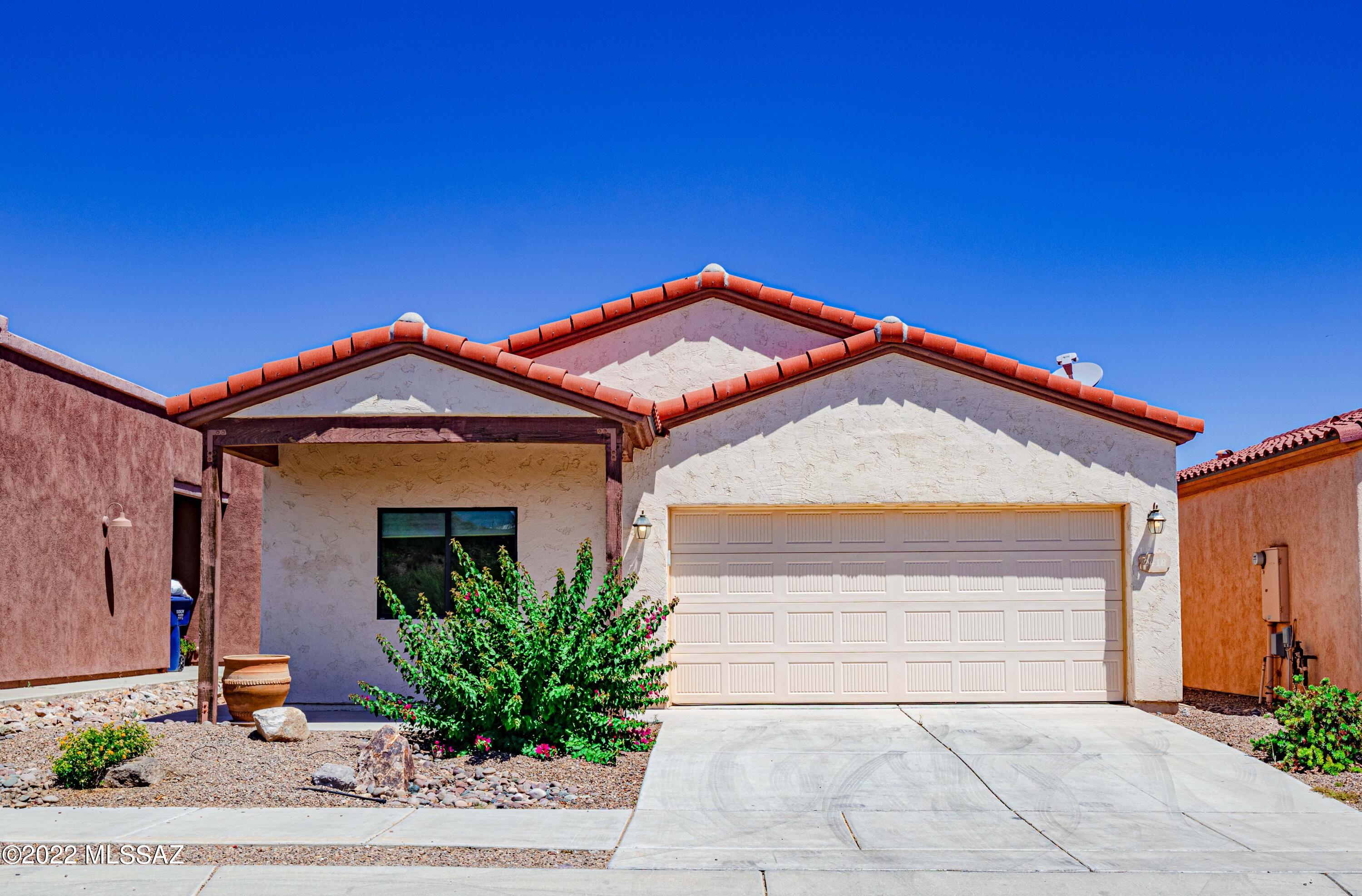 Adorable and newer 3 bedroom, 2 bathroom, 2 car garage, single-story home with a split bedroom floorplan in a private, gated community!  1668 sqft provides lots of storage with many kitchen cabinets, walk in pantry, and generous kitchen island.  Primary suite features double sinks, soaking tub, separate shower, and two closets.  Beautiful tile roof!  Watch the sun rise and set from your low-maintenance covered front AND back porches, with backyard also featuring brickwork and fruit-bearing orange tree! Tile in every room except bedrooms.  Close to University of Arizona, Downtown Tucson, Interstate 10, and Saguaro National Park West!  Good-sized laundry room, and washer and dryer stay!  Make this house your home...today!