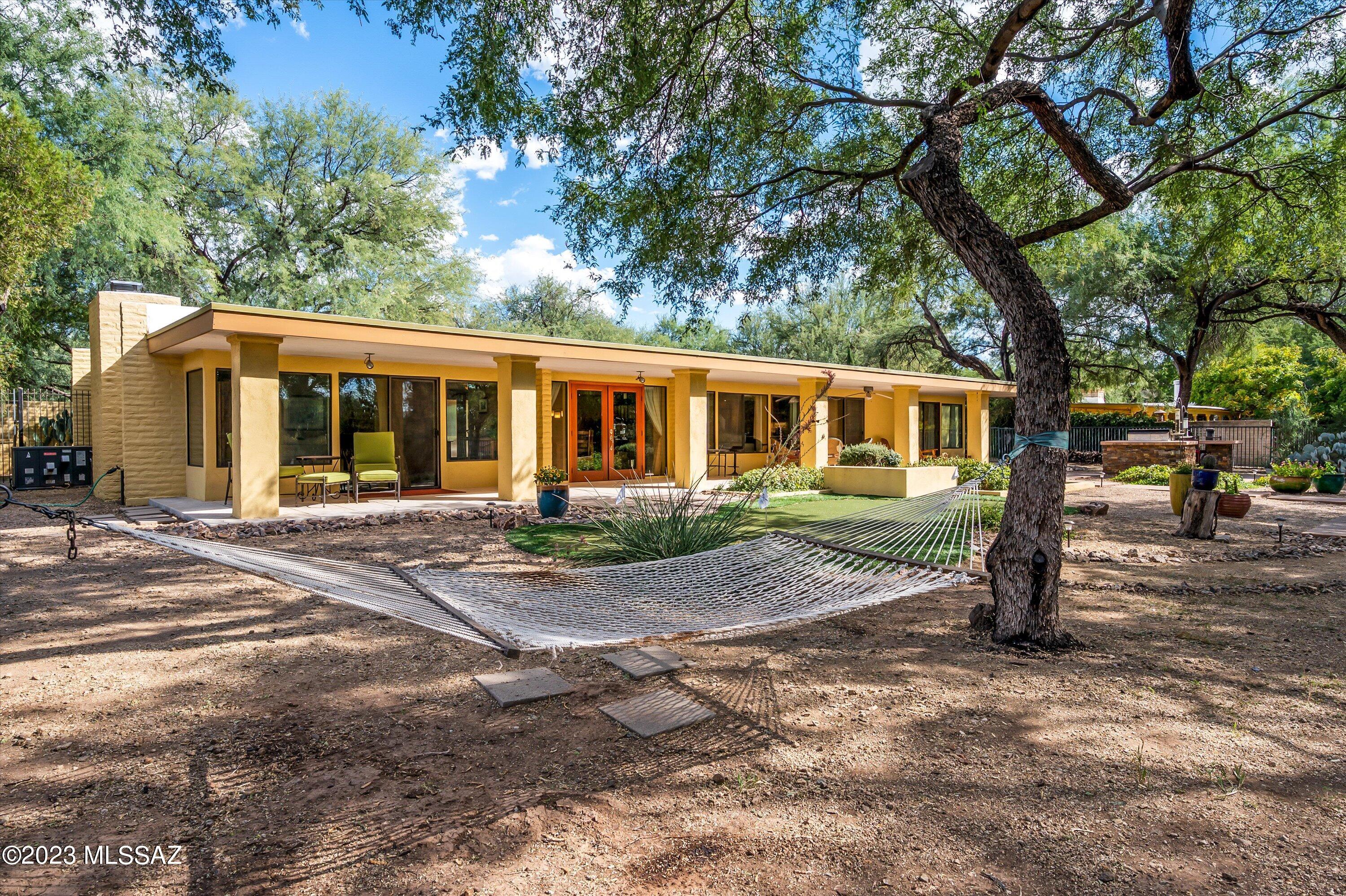 Stunning Mid Century modern home offers 4 bedroom 3 bath is nestled by mesquite trees on the 17th fairway on over 1/2 an acre. Backyard is a desert oasis with gas fire pit, putting green, hot tub, built in BBQ and expansive covered patio to enjoy sunsets and golf course living. Tastefully remodeled gourmet kitchen with convection oven, gas cooktop, wine fridge,  quartz island seating and abundant cherry wood cabinetry. This open split floor plan boasts wall of picture windows and sliding glass doors. Primary suite is a sanctuary with private courtyard. Masonry constructed home with wood and travertine flooring. Friendly neighborhood with driving range, fitness center, restaurant with a variety of memberships available.