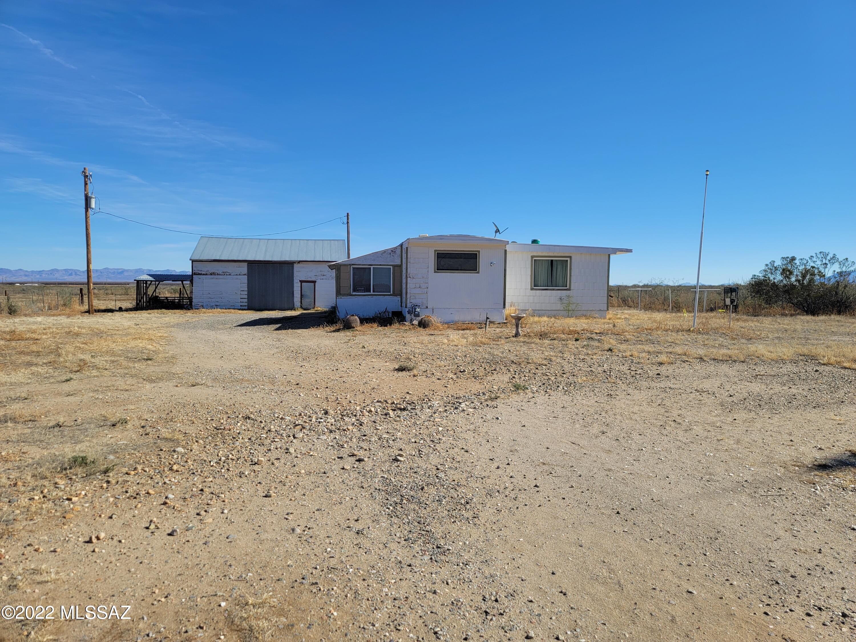 BOWIE, AZ -County Retreat.  This 3 bedroom 1 bath Manufactured home is waiting for you to create a Home away from Home.  Bring your Animals and RV and enjoy the Sunshine and warm Weather!  The property consists of 21.12 Acres, Multiple Storage Sheds/ HUGE Shop / Barn with Loft and 2 separate sides to divide the Storage and work space, NEW Well installed  in 2016 @ a Cost of $17,728 - 640 feet deep/ Static water 518'/ Well Casing to the depth of 593'. This property used to be a Watermelon Farm.  There is an Old irrigation well that is Non-Functional still registered and on the Property. 
Property is sold in AS-IS Condition, All personal Property will remain. Cash and Conventional Loans only due to age of Manufactured Home.