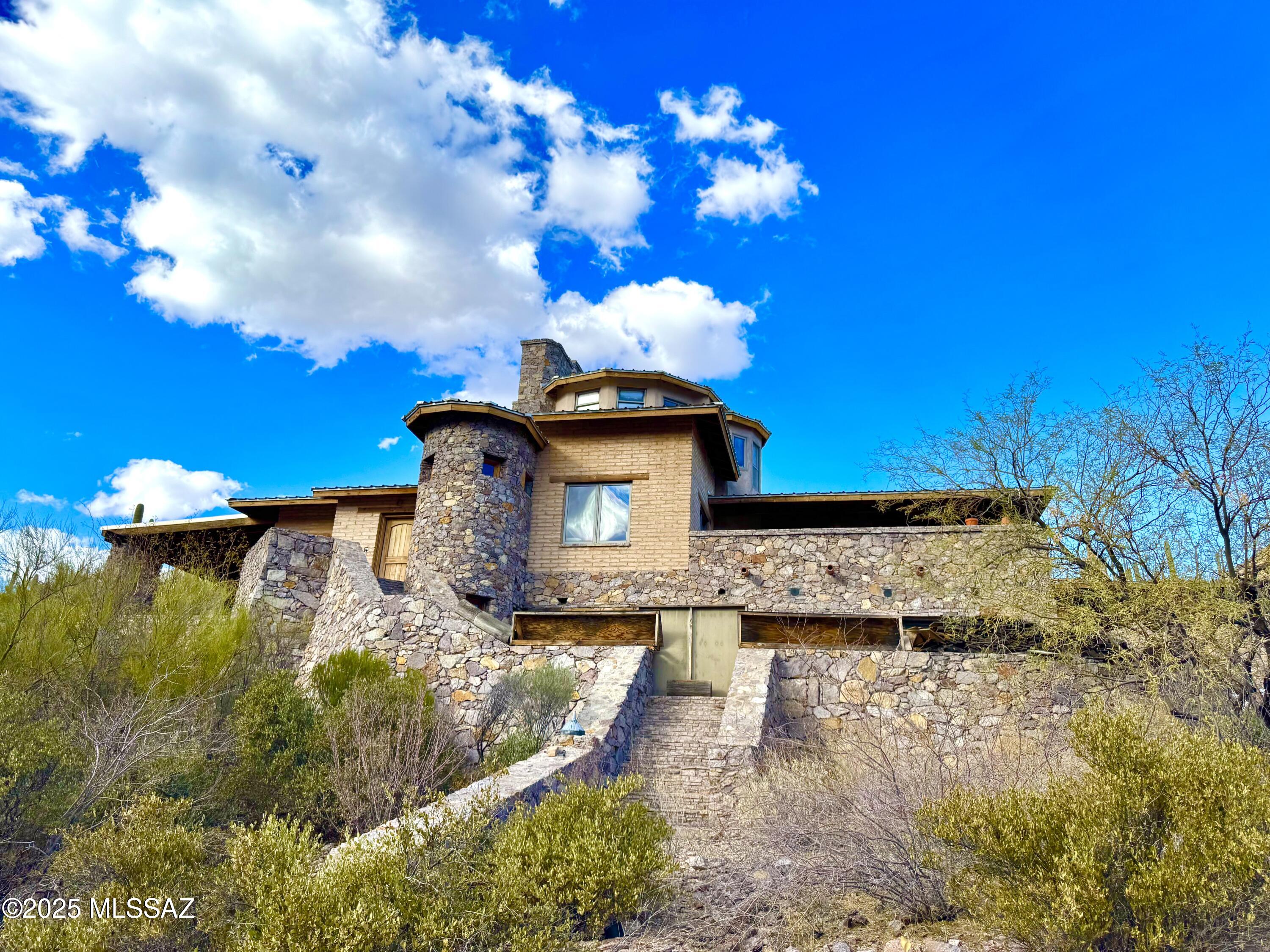Wow!!! Check out one of the most unique homes you'll ever see located on 15 acres of pristine untouched desert in the Tucson Mountains. Built from the Rhyolite of the earth surrounding it, this amazing structure is reminiscent of a castle with 8 fireplaces, multiple secret rooms, a tower loft, a Kiva, and even an underground wine cellar! Every side of the home has outdoor living space with many covered patios, hidden grottos, balconies, and decks to admire the nature you are immersed within. Bound on each side by National Park land and the University of Arizona Desert Research Station land gives you total privacy without the fear of anyone building next to you. Or you can split the lot to build several more homes! Bring your vision to put the finishing touches on this solid masterpiece! Listed as a fix up due to the unfinished flooring in some rooms, an unfinished bathroom, and many missing lighting fixtures. A little bit of personal touch will go a long way to customize this home and make it your own!