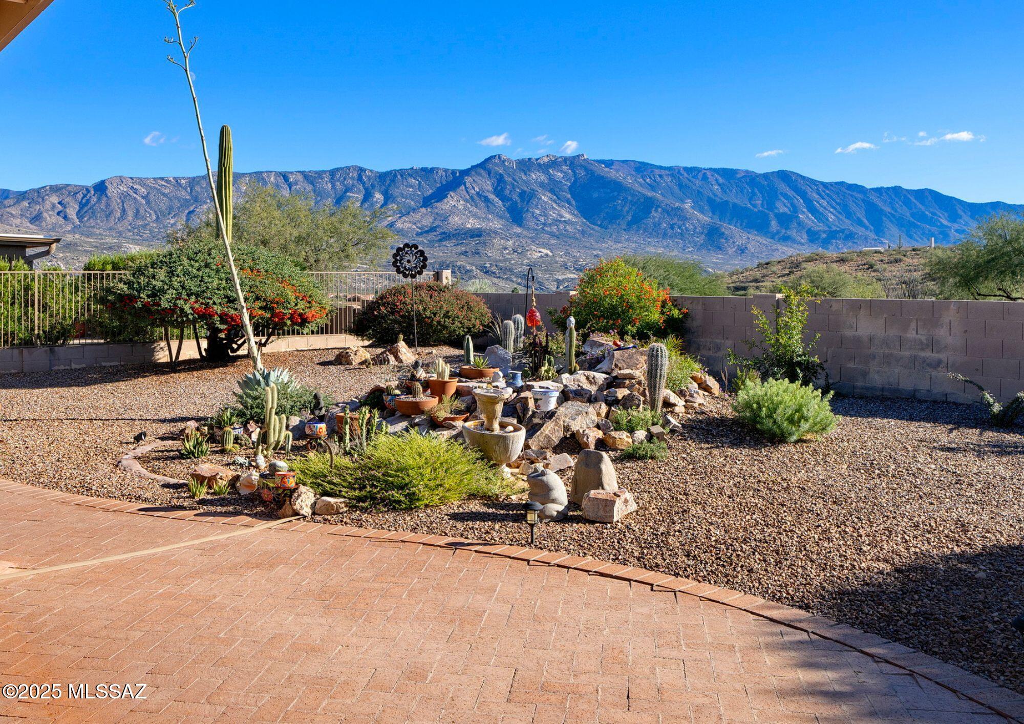 This Laredo model with panoramic Catalina Mountain views is immaculate and ready for new owners! Perfect for a winter retreat or a full-time residence, your new home has panoramic mountain views and a flexible floorplan.  The front courtyard with a peaceful fountain greets visitors and has plenty of room for outdoor furniture. A security screened vestibule allows for cross breeze at the entry of the home. The gorgeous open living space features a vaulted ceiling with skylights, large windows showcasing mountain views and a flip-switch gas fireplace for chilly desert nights. 
Open to the living space and divided by a breakfast bar, the kitchen offers granite slab counters, an island with additional barstool space, closet pantry and all stainless-steel appliances including KitchenAid microwave and dishwasher, Samsung Flex-Duo range (ability to convert into a dual oven) and a Whirlpool French door refrigerator. A dining nook adjacent to the kitchen overlooks the courtyard and will easily with space to easily fit six. This flexible floorplan has a den off the living space that could be converted into a third bedroom. An additional pocket office with a built-in desk is located between the kitchen and laundry room and could also be used as additional pantry space.  
The large primary bedroom also offers mountain views and access to the outdoor space via a sliding glass door. The primary bath has a clerestory window, dual sinks, a walk-in shower and private lavatory. The primary suite is completed with a generous walk-in closet. 
On the other side of the home, the guest bedroom also has mountain views, and is serviced by a full hall bath. Enjoy the outdoors any season of the year from your southeast facing extended covered patio. The rear outdoor space with sweeping views also has a built-in BBQ and mature plantings. 
Storage abounds in the 2 ½ car garageuse the extra bay for a golf cart, workshop area or whatever suits your needs.