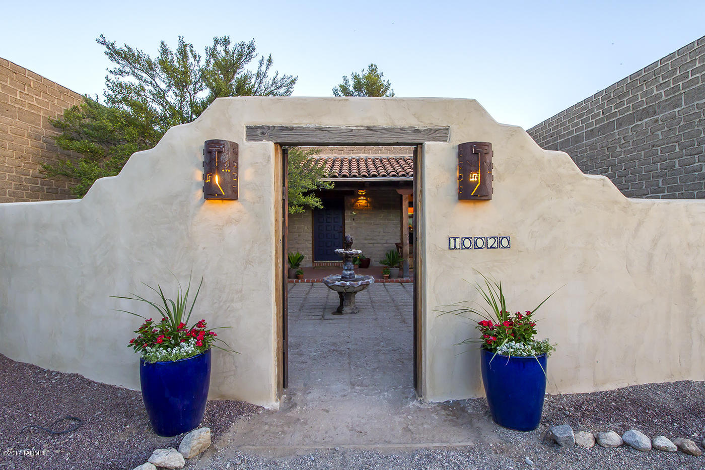 This beautiful, custom adobe Hacienda is situated privately on a lush desert acre. There are gorgeous mountain, sunset and sunrise views. The floor plan flows well and is spacious and very open. There are high beamed ceilings, thick walls, brick floors, beehive fireplace, mexican tile, custom doors and high end windows. There are private courtyards and deep porches to experience outdoor dining and entertaining. The pool is deep and sparkling. The design of this home is timeless and the living is luxurious. Don't forget to view the 3D Virtual tour!