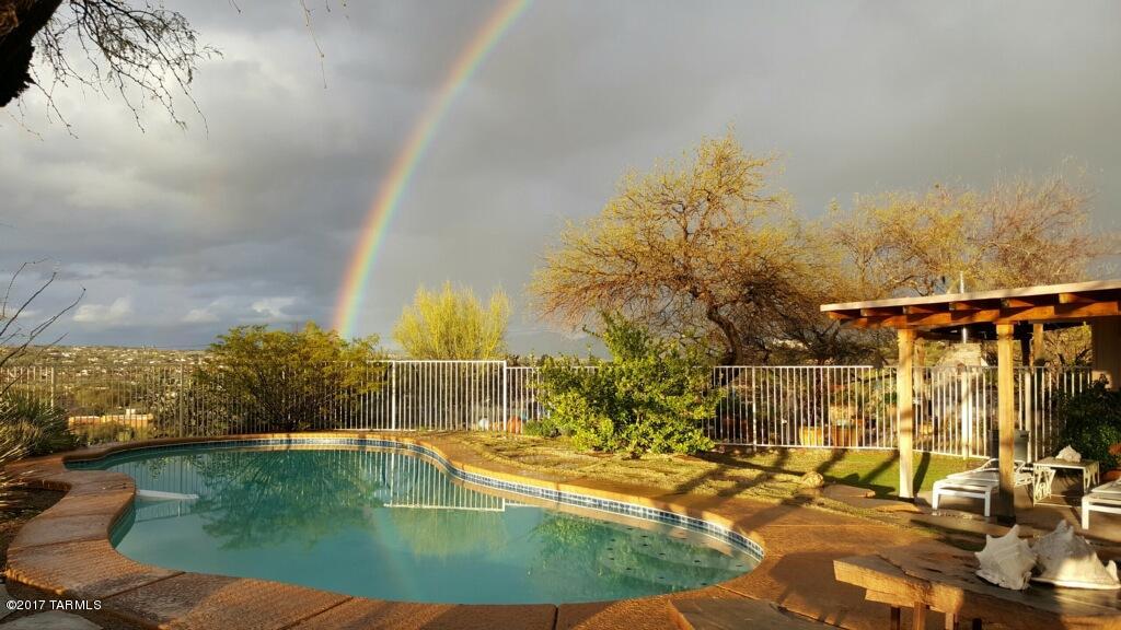 This home is a place of peace & serenity.  Sitting high on a hill, smack dab in the middle of Oro Valley, this treasure is sheltered by lush desert trees & vegetation , while still providing spectacular views of the sunset & a sense of privacy hard to find in these parts. This 2200sf home sits on 2.68 acres. (yes, you can divide it.) If you are looking for a cookie cutter home, this is NOT it.  This home is for those who seek a sense of quiet, well being & a connection to the desert. The patios surrounding the home are designed with desert living in mind.  Imagine spending the morning in the Sun Room or on the front patio, with your breakfast & coffee, welcoming the day. Lunch or dinner would be best served on the North patio…why not, when you have an authentic pizza oven? The crystal clear swimming pool on the west side is simply the perfect place to cool off or watch the lights come on in Oro Valley from this hilltop perch.  Written over the door in the sunroom are the words, " Walk Gently on the earth sharing good wine  & good fortune." That is how this house has lovingly welcomed her guests.  Inside, saltillo tile & exposed block create the foundation for the space.  The remodeled kitchen is thoughtfully designed with authentic materials & finishes...the Sodalite Blue granite island top is a marvel in itself.  Stainless steel countertops & appliances, custom cabinets, range hood help complete this "Cook's" kitchen.  The living spaces are intimate and welcoming, with a generous dining room and artfully built living room with clerestory windows to bring in the glow of the morning sun.   Both bathrooms have been remodeled and there is a huge laundry room.  Three bedrooms complete the living area.  
 Oh, lest we forget, there are horse facitlities , tackroom, & arena.  Designated horse trails & access to Catalina State Park are right off your driveway!  
This home is the perfect marriage between the desert living and excellent location.  Make it your own.