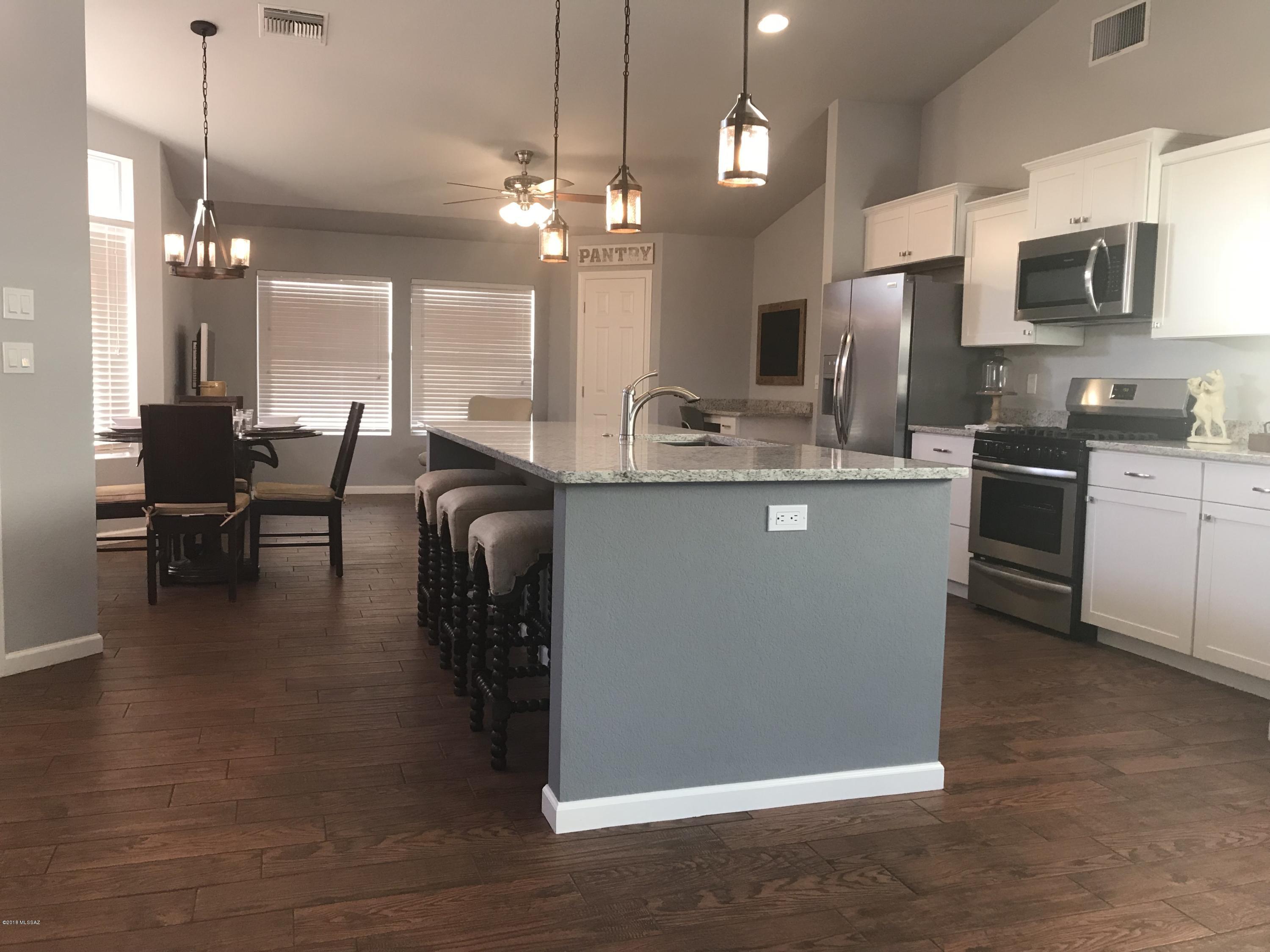 Stunning remodel in a highly sought after neighborhood. This home has a modern, open feel with tons of natural light and great space. All new kitchen cabinets, SS appliances, granite countertops, large island with tons of counter space and a huge pantry. Wood looking, easy care, ceramic tile floors throughout main living areas, fans in every room, updated recessed lighting, new paint & carpet, large laundry room & great storage throughout. The backyard is set for entertaining with brick pavers and low care artificial turf. Peekaboo view of Catalina mountains & no neighbors to the rear of the home. Poly pipes replaced in 2013. Low HOA dues w/community pool, spa, tennis courts, clubhouse, playground & walking paths. 1 yr home warranty included. Owner/Agent/Contractor This neighborhood is extremely well maintained, low HOA dues, & has wonderful amenities including 2 community pools, 2 tennis courts, a clubhouse for entertaining, shaded playground and sidewalks for exercise all around.Owner/Agent/Contractor.