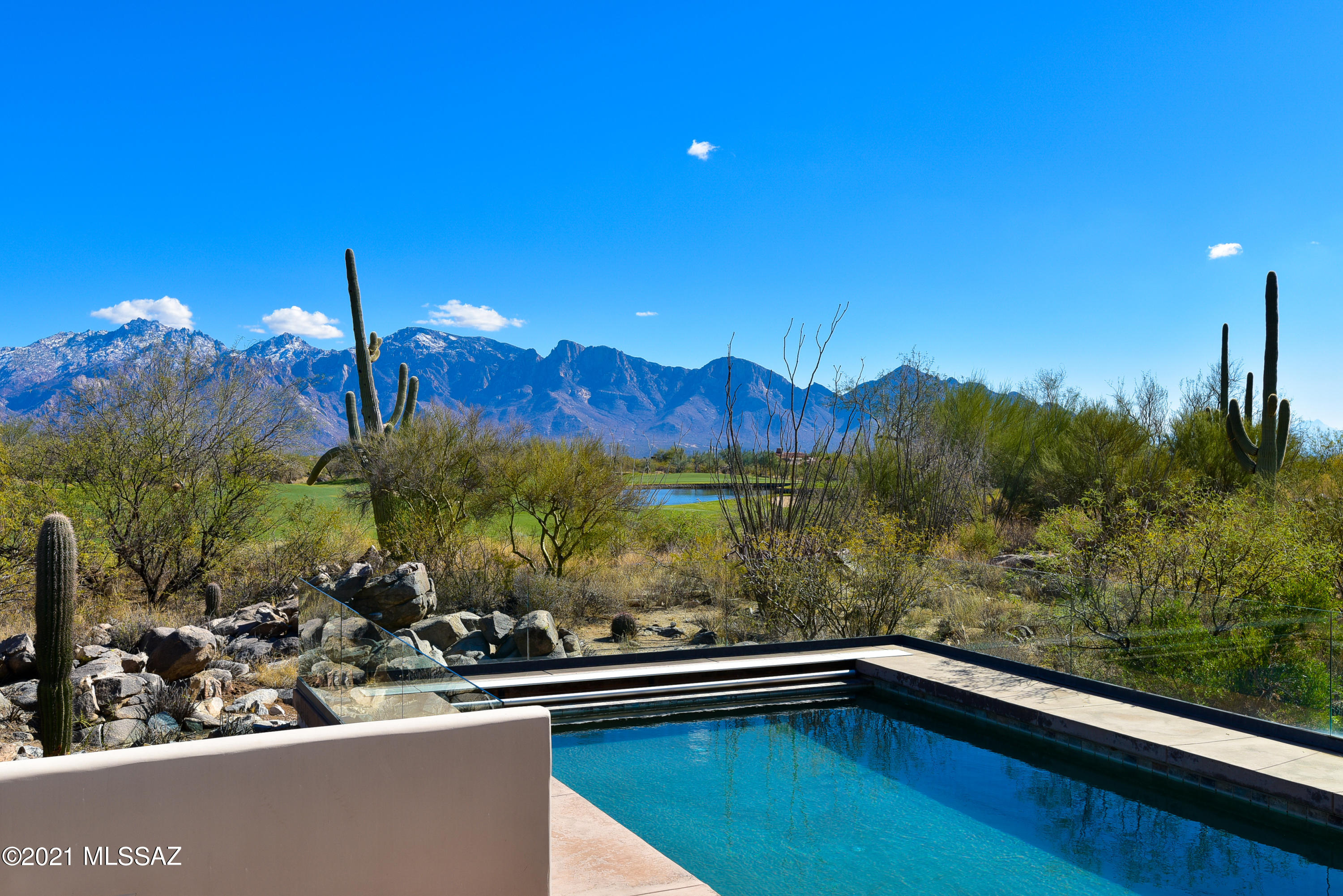 Panoramic views over Stone Canyon's 10th fairway & lake of the majestic Catalina Mountain range. Designed by renowned local architect Ron Robinette in an arc layout, this marvelous 5 bedroom home has it all: large master with private patio, sauna, exercise area and glass enclosed hot tub room plus 4 suites (3 large suites have patio access), gorgeous chef's kitchen with 2 D/W and 2 Sub-Zeros, wetbar/butler's area, large office and solid masonry construction. Spacious patio with fabulous pool!  Very private setting off cul-de-sac offers serenity and seclusion. Oversized 3-car garage includes work space and storage. High ceilings, floor-to-ceiling windows & curved halls create marvelous spatial elements for bright indoor living. Sold in current cond. Exterior painted 2021! Membership req'd.