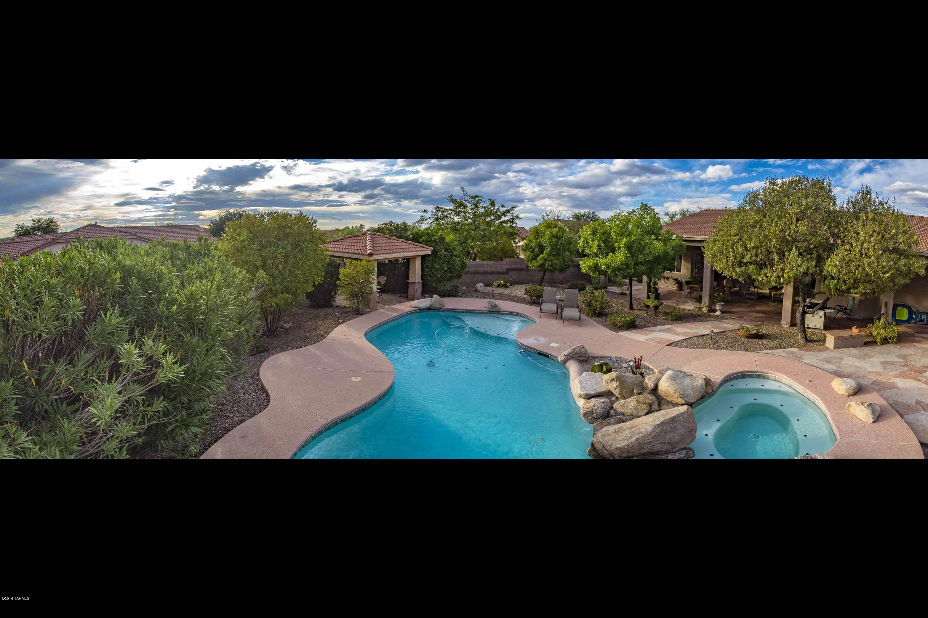Elegant home with many custom features.  Large well appointed kitchen with granite counter tops, Frigidaire Professional SS appliances, many extra cabinets, all with pull out shelves, built in desk area.  Formal and informal dining areas.  Living room and family room with pretty stone faced fireplace. 3 generous sized bedrooms plus an office just off the foyer.  Travertine stone floors with mosaic design in foyer.  Custom paint throughout.  Entertainers dream covered patio, plus uncovered patio with fireplace, pool and spa with waterfall feature and Ramada. Mature trees provide great privacy on this corner lot.