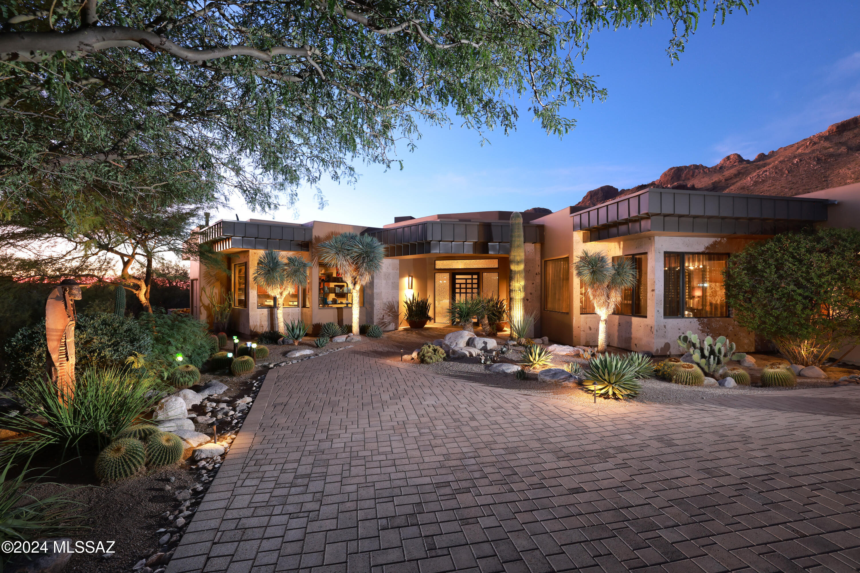 Presenting an architectural marvel in the prestigious guard-gated community of Pima Canyon Estates, offering an unparalleled fusion of sophisticated design and natural desert beauty. Nestled amidst panoramic views of the rugged Catalina Mountains, this stunning 6,300+ sq ft Southwestern Contemporary exudes elegance at every turn. With a commanding presence, this 5-bedroom, 5-bathroom residence is a sanctuary of style and comfort, designed to elevate modern living.

Step into a sunlit haven, where expansive windows, soaring ceilings, and 24x24 sandstone flooring create a luminous, airy ambiance. The chef's kitchen is a masterpiece in itself, reimagined with impeccable attention to detail: custom cabinetry, sleek quartz countertops, a refined tile backsplash, and premium appliances including a Sub-Zero refrigerator/freezer, dual Viking ovens, and twin Miele dishwashersensure every culinary experience is exceptional.
The luxurious primary suite is a retreat of unparalleled comfort, featuring a marble-faced fireplace, retractable solar sunscreens, and custom shades for optimal privacy and elegance. Off the dining room, a show-stopping glass and mahogany wine cellar creates an intimate setting, perfect for hosting conversations over your favorite vintages, all maintained at ideal temperatures with dedicated climate control.
Step outside to an oasis of tranquility and luxury. The meticulously landscaped grounds are a testament to masterful design, featuring lush desert flora that seamlessly blends with the natural surroundings. The custom cedar-lined ramada with sandstone flooring provides a serene setting for outdoor relaxation and entertainment. Here, you'll find a sparkling pool and spa that invite leisurely afternoons, while expansive patios offer breathtaking mountain vistas.
This meticulously curated home is further enhanced by a state-of-the-art audio/video system, new chandeliers, and custom cabinetry in the office. Enveloped by professionally designed landscaping and thoughtfully upgraded to perfection, this residence epitomizes refined desert living. Experience the height of luxury in Pima Canyon Estatesschedule a private showing today.