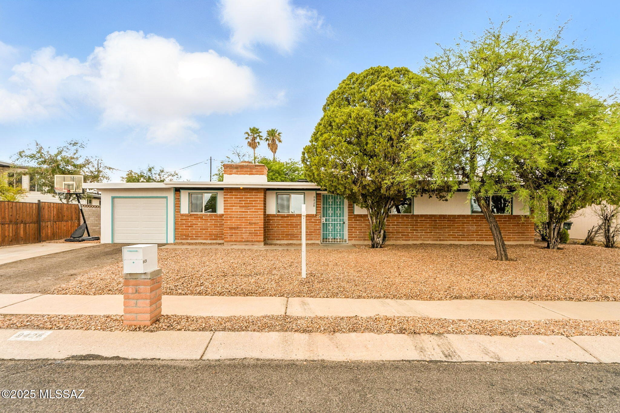 Hard to find at this affordable price, this well-loved mid-century brick home sits in a quiet east-side neighborhood. You'll immediately be impressed by the curb appeal with pops of white and turquoise that perfectly complement this classic desert home. A welcoming foyer makes a great drop zone for bags, shoes, and keys. The cozy living room features a wood-burning fireplace, projector and screen for movie nights or sport watching parties, and updated recessed lighting.

The kitchen is a standout with an incredible amount of counter space and cabinetry, two ovens, a butcher block island, a pantry, a long buffet/serving area with additional storage, and all appliances included. A large dining area and bonus family room offer French doors to the backyard.

The spacious primary suite includes a fully updated bathroom, private door to the backyard and laundry area, and a hidden safe in the closet. Additional bedrooms are well-sized, and the guest bathroom has been fully updated including a glass tub/shower enclosure. The hallway offers convenient built-in storage, and there's no carpet, hard flooring throughout. 

An extended-length garage and a huge detached storage/workshop in the backyard provide plenty of extra space. Solar panels help keep electric bills low, and fresh gravel in both the front and back yards make for easy-care outdoor spaces with mature shade trees.

Located within walking distance to popular Jesse Owens Park, featuring a lap pool, walking trails, basketball courts, playgrounds, baseball fields, and a brand new splash pad.