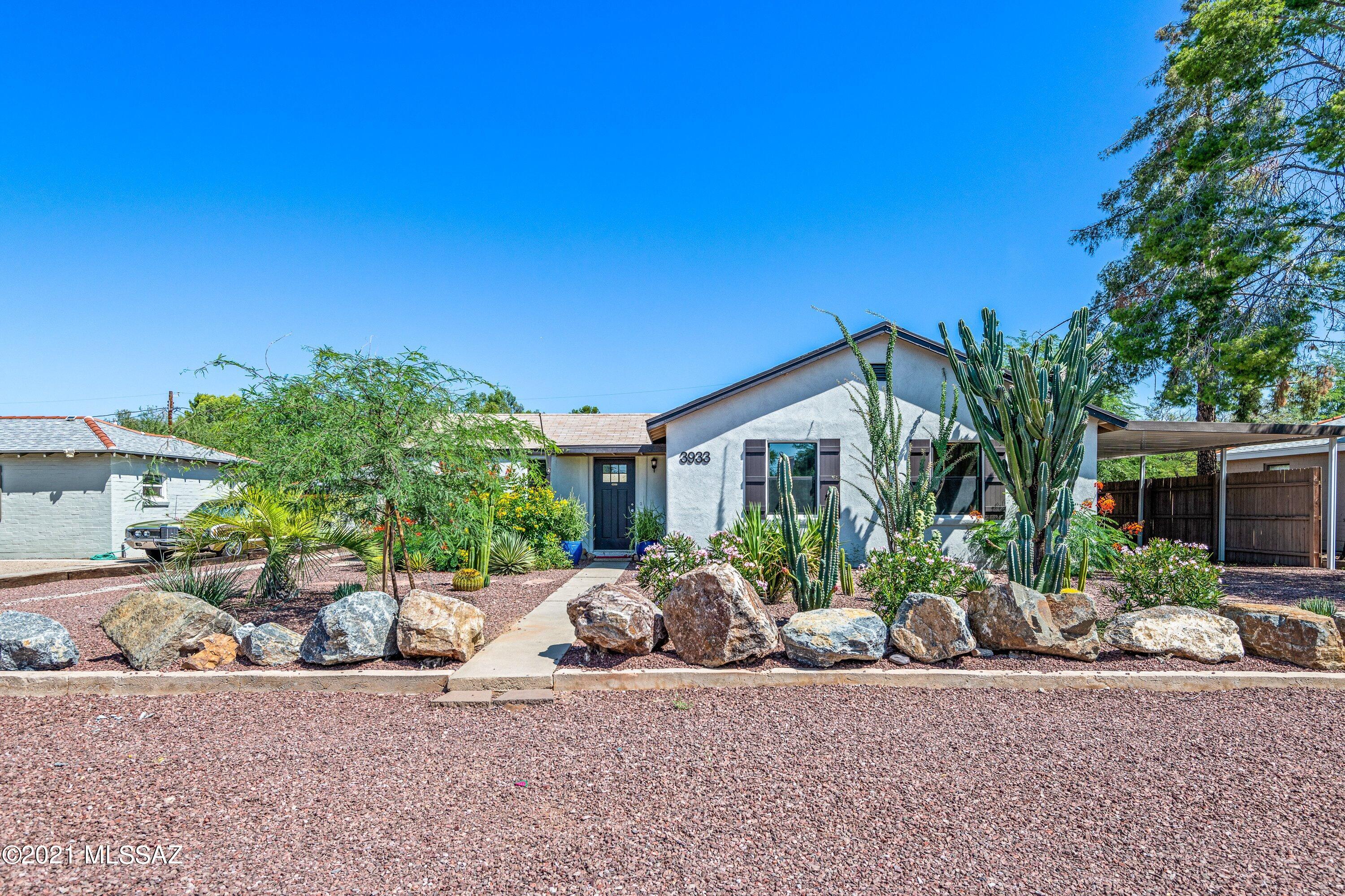 In the heart of the central Tucson sits a beautifully updated mid-century home with perfect mountain views. Before you enter the home, you're greeted by a beautifully designed front yard, featuring native plants. The bright open feeling begins the moment you walk through the door to a great room concept ideal for entertaining. Feel the natural light shining through the windows, lighting up this 3 bed/2 bath home. Kitchen features granite countertops, all stainless-steel appliances, and oversized pantry. Spacious primary bedroom features vaulted ceiling, sliding door looking into neatly manicured backyard, huge walk-in closet with custom shelving, en-suite with dual vanities and walk-in shower. Newly painted interior and carpet, fans in every room, and laundry room includes washer/dryer. Step outside into the lush, meticulously maintained backyard with low care synthetic grass offering the deep green color all year, and 2 additional covered paver patios perfect for table and chairs or a hot tub under the stars. Additional structure in backyard can be used as a home office, den, or studio. Extended length carport with additional parking pad perfect for RV or trailers. Minutes from dining and shopping, this home is a few blocks from the Tucson Botanical Gardens. Enjoy all the unique experiences Tucson has to offer.