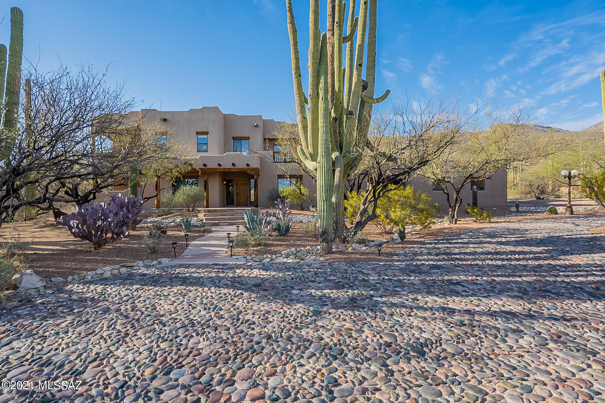 Welcome to this Sante Fe style home on 3.73 acres nestled against the beautiful Catalina mountains. Drive up to your private, remote access gate onto a cobblestone roundabout. 4 beds+DEN with Southwestern touches throughout! Soaring 23ft tall exposed beam ceilings in the main family room, gorgeous Saltillo tile, rustic wooden lintels, and kiva masonry fireplace. French doors off the family room invite you to enjoy this desert oasis backyard. Heated pool and spa with built-in water slide and waterfall.  Beautifully landscaped artificial grass, firepit, flagstone and desert vegetation. Overlook your serene backyard against the picturesque mountain views from your kitchen window. The gourmet kitchen is a cook's and entertainer's dream come true, featuring Viking appliances, gas stove, custom copper exhaust hood, granite countertops, huge island and large pantry.  Tons of storage throughout the home (make sure to check out the closet underneath the stairs). Elegant formal dining room.  Retreat to your Master bedroom's private balcony patio. Master bathroom has heated flooring, luxurious jacuzzi tub/shower, and huge walk-in closet. Upstairs has 2 loft spaces/nooks that could be used as a playroom, library, work from home, homeschool, home gym, endless possibilities!  Common area balcony upstairs for watching the sunset, hosting, and relaxing!  Upstairs laundry shoot to the laundry room downstairs!! Large 2-car plus RV garage and hobby/workshop.  216sqft guest casita with ¾ bath and closet--just walk across the breezeway to the main home kitchen!  Zoned horse property, close to hiking and biking trails, no HOA, and tons of privacy.  Pride of ownership shines in every part of this lovingly maintained home!