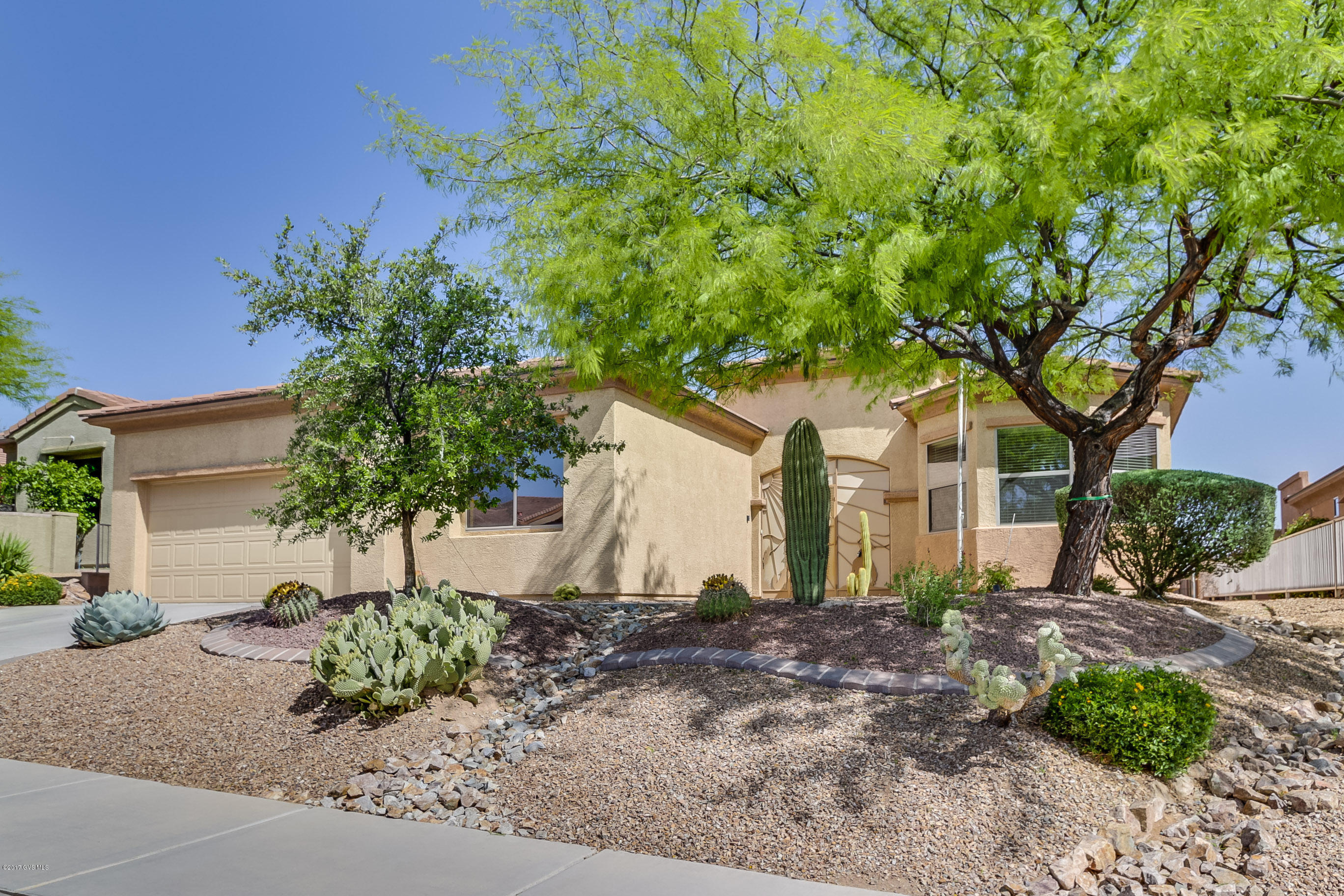 Crisp landscaping, a shady mesquite tree, an amplified octagonal window and a fully screened front entry foyer tells you this home tour will be special. The great room has a bank of windows with warm gas log fireplace flanked by double media niches and wall mounted TV. The island serving bar directs your pathway into a kitchen with gorgeous granite slab countertops and an upgraded stainless sink set under the counter for easy cleanup. The convenient dining area is surrounded by a bay window for taking in expanded desert views. Don't miss the bonus wing that grants you a den with an additional bedroom, library, office or workout room with rich wood flooring behind double French doors. The master bedroom suite has a bay window sitting area and a spacious bath with separate his and  hers vanities, designer faucets and custom tile backsplash. And, your overnight guests will love their suite with bay view window. This popular San Dimas model is also complete with the expanded laundry/room area. The roomy backyard offers spaciousness while the simple desert landscaping features flowing river rock and low maintenance cactus gardens for ambiance. The back patio has an extended brick patio giving you a sunny spot for relaxing while enjoying the relaxing sounds of the trickling fountain. Freshly painted and just waiting for you!