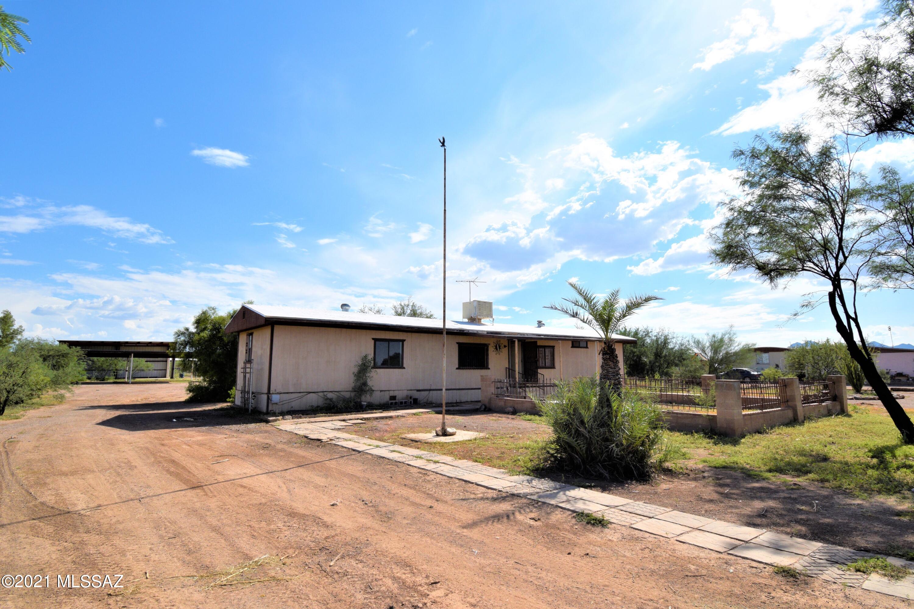 Great opportunity for a massive fix up. Home h;as 2 bed and 2 bath, huge RV Garage/Carport or Hay Barn etc. Also has SW Gas, large 1+ acre lot fully fenced with beautiful iron work on gates and entry. This home is AS IS only and can ONLY be cash sale. NO Owner financing, no financing available due to condition. Floors have soft spots and will need repair, cabinets, drawers etc have been damaged. The true value is in the out buildings, aviary/chicken coop, animal corral, and land fully fenced. This home could be renovated and fixed up, or could be removed for a new unit or home to be built. All appliances are in unknown working condition. EVAP cooler does turn on and respond to both fan and cooler mode but all is unknown condition and age.