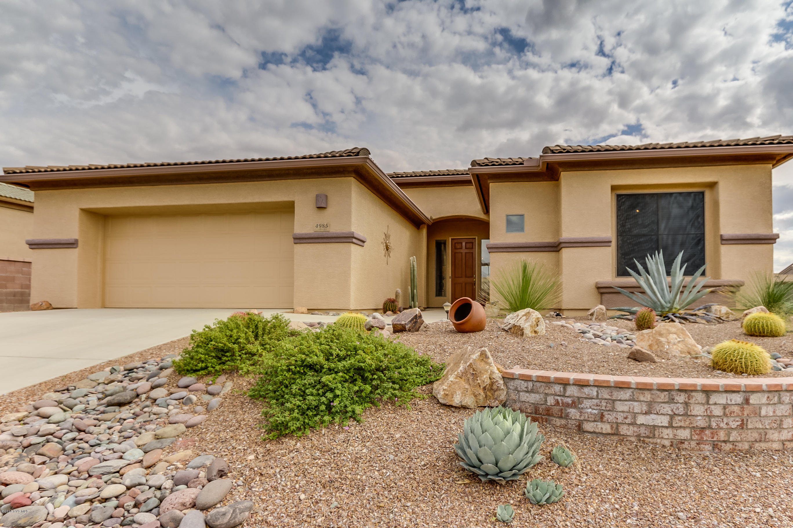 This beautiful Arlington model home offers an open concept, arched doorways and desirable split bedroom floor plan. The warm space is 1861 Sq.' with two bedrooms, two baths and a den making it the ideal size for many. The great room has a gas fireplace, attractive built-ins and lots of widows that allows natural light to flow in. The home has mostly tile flooring with cozy carpet in the bedrooms and den complemented by a neutral paint color throughout. The kitchen has an attractive custom tile back-splash, pantry closet and a serving counter. The entire yard is beautifully landscaped from the excellent curb appeal to the backyard fountain, fire pit and barbecue ideal for entertaining. The slightly elevated lot provides backdrop views of the mountains just beyond the neighboring homes.