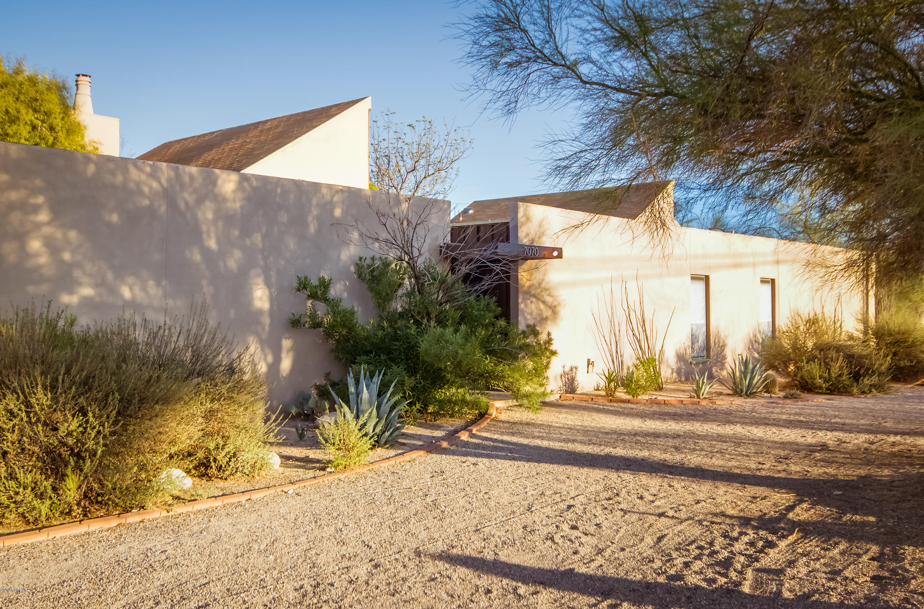 Don't worry about the address because home is set well back from La Canada with natural buffer in between. Private lot with long driveway with plenty of room for cars, toys, etc. Natural desert landscaping & charming courtyard to impressive double door entry.  Contemporary custom home with lots of windows and sliding doors for natural light. Great Room has a loft for library/den with the only stairs in home. Spacious updated kitchen with tons of cabinet and counter space plus pantry. Huge master bedroom with private sitting area and updated master bath.  Enjoy your own greenhouse connected to kitchen to grow herbs and tomatoes for cooking! Private yard with lush desert landscape & mountain views from back patio.