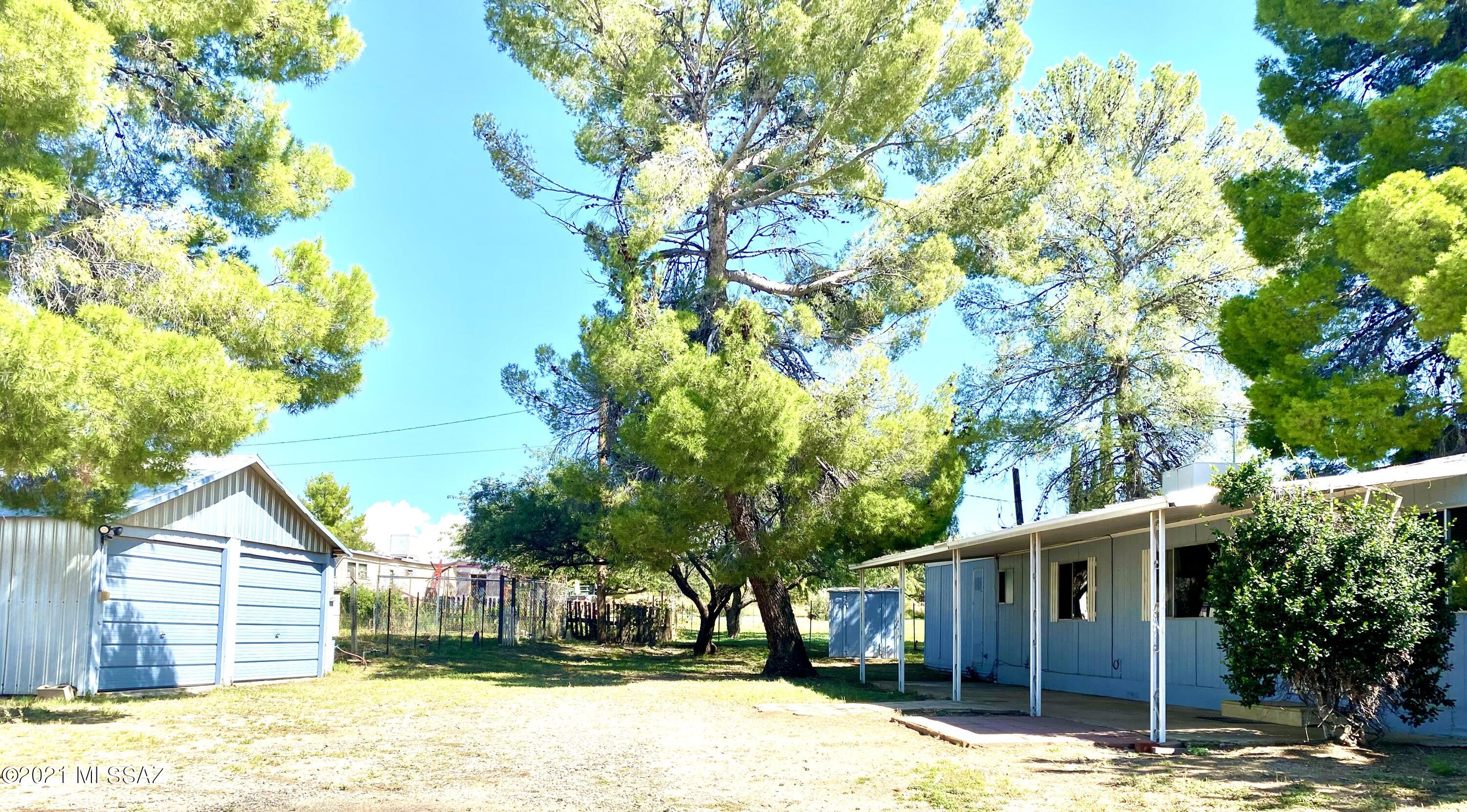 Great home near the Oracle school.  This lot is fully fenced and has beautiful trees! Large covered porch on the home. There is a detached 2 car garage and 20 x 24 garden area and chicken coop.  Plumbing in the home was replaced with PVC.  Sewer pipe from home to the street was replaced with 4'' PVC. New carpet throughout. Master Cool evaporative cooler. Bathroom has new toilet and new vanity mirror. This home is being sold in AS IS condition.  Home is tied down and is not affixed. Cash buyers only.