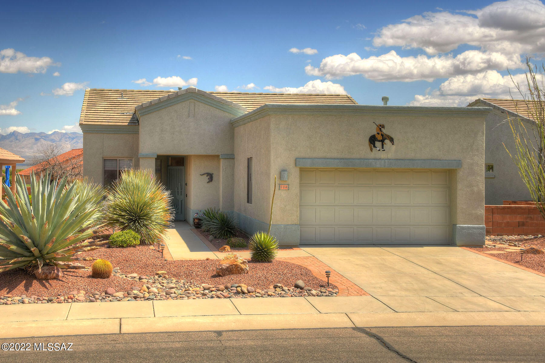 Backing up to the mountains and surrounded by lush desert landscaping, this home was built for entertaining and an outdoor lifestyle! Santa Rita Mountain views will captivate you from both inside and out!. A beautiful front entry impresses guests and the large great room is spacious enough for any event. A roaring fireplace adds interest and warmth on chilly desert evenings.  The open kitchen is incorporated into the great room  and allows guests to mingle with the chef.  A breakfast bar accommodates extra guests. Newer gleaming stainless appliances  add a bit of luxe. The dining area features sliders leading out to the gorgeous covered patio and those mountain views! A separate den is adjacent and perfect for a private TV room, hiding your crafts and hobbies, or extra room when winter guests arrive.   The master bedroom is spacious and features a bump out for extra space and beautiful mountain views!   A small bonus room is off of the garage and can be used for extra pantry storage, or a small office.  The guest suite with its own bath is on the other side of the home, allowing for absolute privacy. 
If you have been searching for a desert home that offers a an open and flowing floor plan combined with gorgeous mountain views and outdoor living spaces, then welcome home!