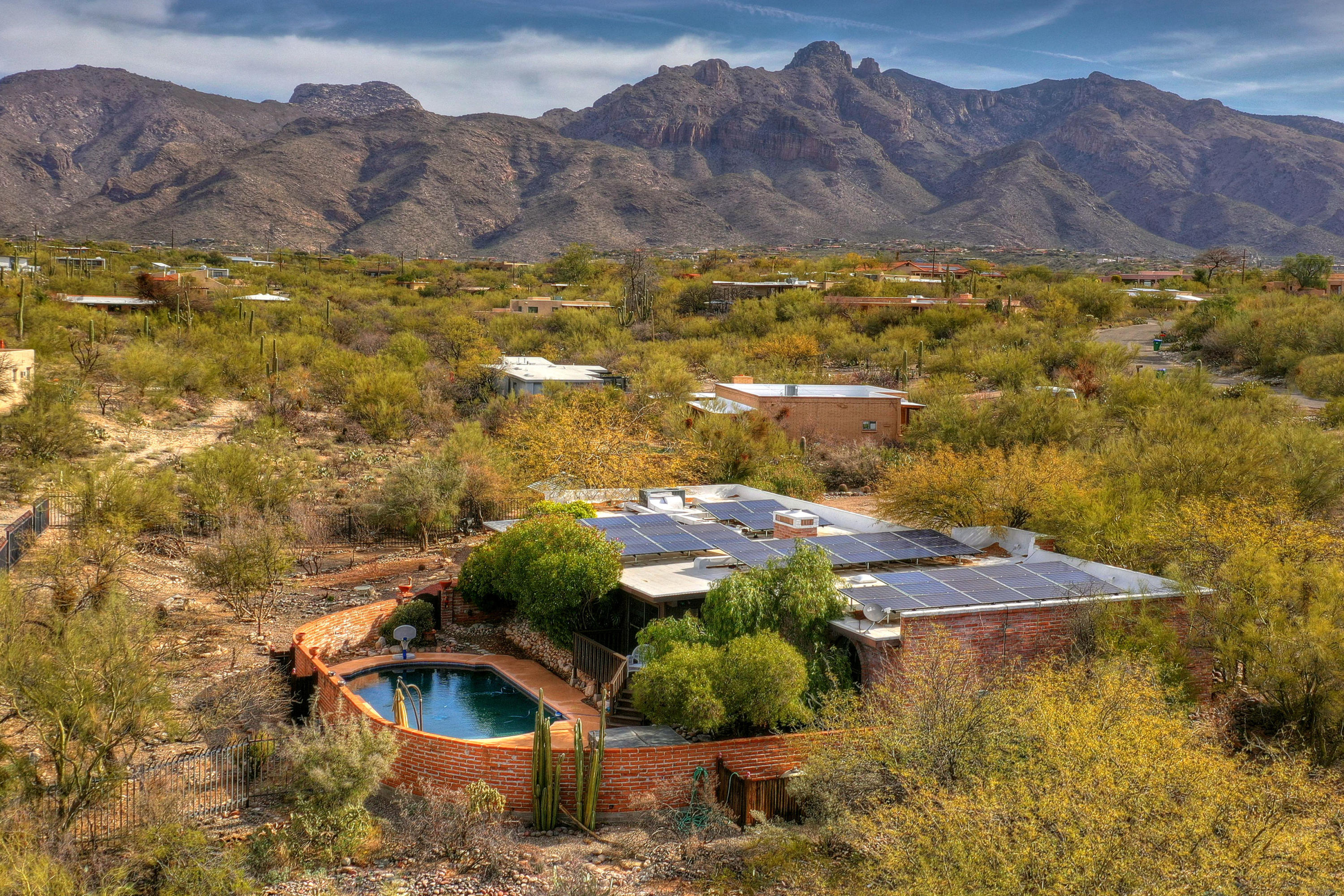Enjoy the beauty of this southwest traditional burnt adobe territorial home. Nestled in the Catalina foothills on .84 acres & surrounded by lush Sonoran Desert. No need to worry about high summer electric bills as home is serviced by Tesla Solar Panels. 4 bedrooms, 3 baths & an Arizona room & game room encompass the 3000+ sqft of living space. Spacious kitchen w/ granite counters & Stainless Steel appliances opens up to the Dining room, family room & Arizona Room. A split bedroom floor plan offers new carpet throughout and a second master suite that can also act as a home office w/ both interior and exterior entries. Plenty of storage exists w/  detached 10' x 20' workshop. Additional amenities include an above ground spa, large enclosed pool area & secondary yard enclosed by steel fencing