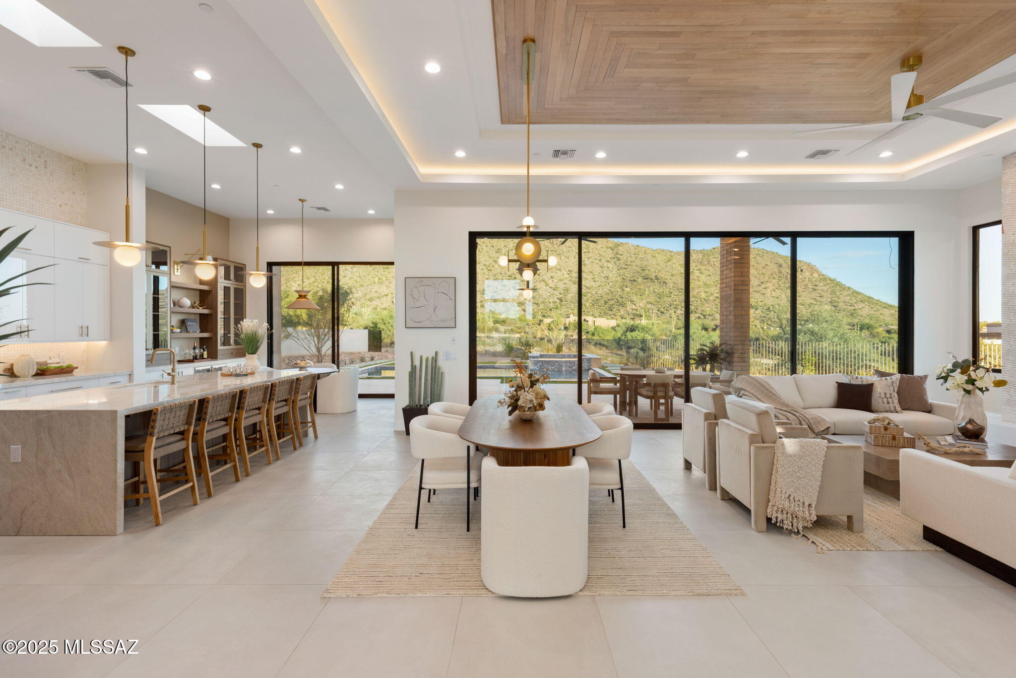 Welcome to Tranquility at The Overlook, a new statement of luxury & intentional design. This newly completed home fuses contemporary architecture w/ the serene spirit of nature. Located in the exclusive double-gated enclave of The Overlook at Gallery Golf Club at Dove Mountain, this residence is surrounded by sweeping mountain & golf course views. Circles & waves are repeated throughout in lighting & imported Spanish tile, reflecting a design philosophy centered on peace & calm. This thoughtfully designed floorplan features three bedrooms each w/ its own ensuite bath, a dedicated office, & a private guest casita. Every element of this home was crafted to evoke calm, balance, & connection to the natural landscape. The moment you arrive, the 12-foot pivot entry door and soaring ceilings create an unforgettable first impression. Natural light floods through walls of glass, highlighting an interior palette of warm white oak, soft neutral tones, and fine natural materials. Every design element was selected with purpose. Circular and wave patterns appear throughout, from high-end contemporary lighting to dimensional Spanish tile, representing balance, peace, and the rhythmic beauty of nature.

The open-concept great room serves as the heart of the home, anchored by a stunning fireplace wall wrapped in imported tile and a floating quartz hearth that glows softly with under-lighting. Above, the custom white-oak ceiling design adds texture and warmth, creating a sense of organic sophistication. Seamlessly connected to the great room, the chef's kitchen is a work of art in itself, featuring flat-panel cabinetry, champagne-gold hardware, a circular marble backsplash, and an expansive quartzite waterfall island with seating for five. A walk-in pantry with butcher-block counters and built-in outlets provides discreet space for prep and storage, allowing the kitchen to maintain its clean, contemporary aesthetic.

The home's layout flows effortlessly from shared living spaces to private retreats. The primary suite offers a spa-like ambiance with fluted tile, polished porcelain, and a freestanding soaking tub perfect for quiet relaxation. Each guest suite features an ensuite bath designed with the elegance of a boutique hotel, complete with backlit mirrors, custom tilework, and refined fixtures. The dedicated office captures tranquil views of the mountains and golf course, balancing productivity with inspiration.

Even the functional spaces were designed with intention. The laundry room pairs playful sage cabinetry with a circle-pattern backsplash that was hand-set tile by tile, blending artistry with everyday utility. The detached casita provides guests with privacy and comfort, including a wet bar, microwave, and beverage fridge for a true retreat experience.

Throughout Tranquility at The Overlook, the design language remains consistent, organic shapes, light natural materials, and a calm tonal palette work together to create an environment that feels peaceful, restorative, and timeless. This is more than a home; it is an experience of architectural artistry and modern refinement, designed to bring balance to the way you live every day.