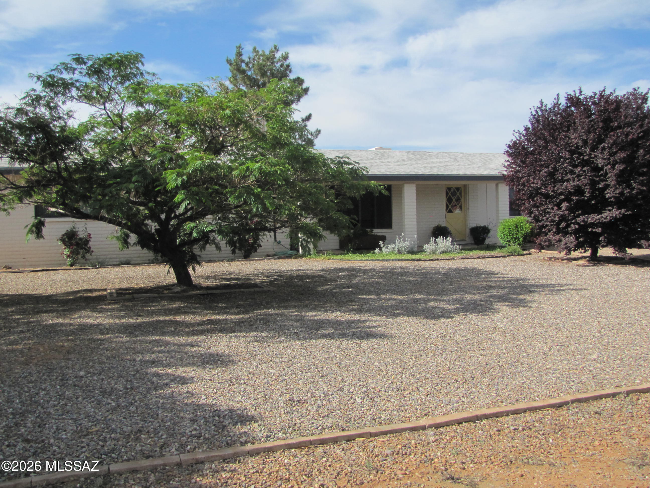 Welcome home! Mature trees and flowerbeds along with a covered patio usher you into this 3BR/2Ba slump block home situated on a spacious 0.84ac lot. Newer roof, plumbing, water heater, windows, appliances & flooring throughout. Lots of natural light and storage. Living room has large window. Open kitchen and dining room with wood burning fireplace. Window at kitchen sink looks onto backyard with more mature trees & grass. Three nice-sized bedrooms down the hall from the kitchen. Extra room between house & garage can be used for office/den/4th bedroom. Sliding door from dining room opens onto covered back patio...perfect place for entertaining or enjoying your morning coffee. The extra room opens onto patio & backyard, and into garage. Drive-thru gates on west and alley side of backyard. Two-car garage with workbench. Located near the amenities in Sunsites. Easy access to Hwy 191 and I-10.