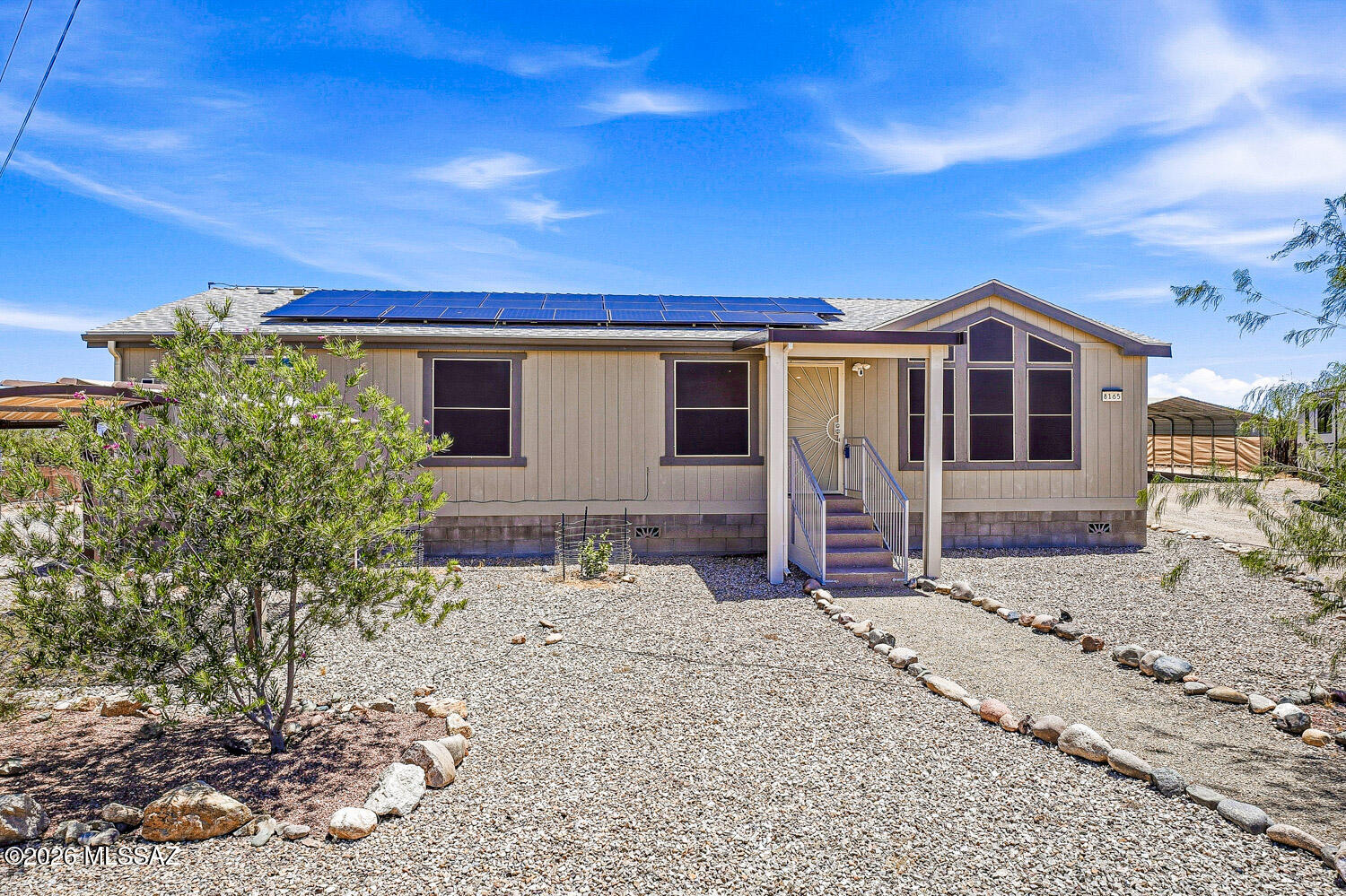 Clean and spacious 1-acre, fully fenced lot featuring a modern 2021 manufactured home - with NO HOA! The seller will pay off the solar loan, so the new buyer will benefit from OWNED SOLAR. Enjoy outdoor living with a covered patio equipped with Trex decking and a relaxing hot tub. The property includes two separate carports (accommodating up to four vehicles), two sheds, a Conex container for extra storage, a greenhouse, a dog kennel, and a cozy fire pit. Additional features include solar screens, fruit trees, a water softener, and durable concrete-block skirting. This property has everything you need for comfortable and sustainable living!