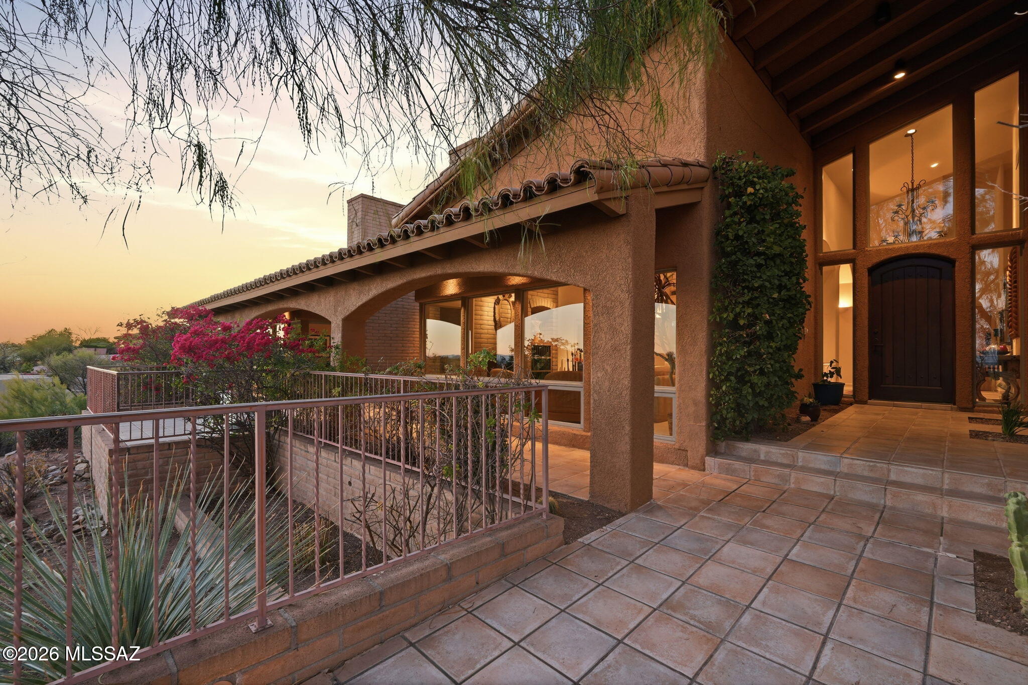 Nestled high within the prestigious gated community of Ridge Estates in La Paloma, this exceptional residence was designed by acclaimed architect John Campisano and showcases breathtaking 180-degree panoramic views of Tucson's most iconic landmarks. From the sparkling city lights and lush golf course fairways to the University of Arizona and vibrant downtown skyline, the vistas are truly unforgettable. An impressive front entryway welcomes you into a home where architectural elegance and spectacular scenery take center stage. Expansive windows throughout the residence frame the stunning views from nearly every room, while soaring ceilings create an open, light-filled atmosphere that enhances the home's sense of grandeur. Offering 5 bedrooms and 4.5 bathrooms, the thoughtfully designed floor plan blends luxury and comfort. Two spacious living areas, each highlighted by a striking fireplace, provide inviting spaces for both entertaining and everyday living. Beautiful hand-carved doors lead to the private west wing of the home, adding warmth, character, and distinctive architectural detail.
The oversized chef's kitchen is perfectly positioned to capture magnificent mountain views while overlooking the resort-style pool and spa, creating an ideal setting for gatherings with family and friends. A hidden butler's pantry, discreetly concealed behind custom cabinetry, adds both sophistication and functionality while preserving the kitchen's clean, elegant design. Seamlessly connecting indoor and outdoor living, the home embraces Tucson's natural beauty at every turn.
The luxurious primary suite serves as a private retreat, complete with two large walk-in closets and generous space designed for comfort and relaxation. Thoughtfully positioned to take advantage of the home's elevated setting, it offers a tranquil escape at the end of the day.
A private driveway leads to the 3-car garage, enhancing the property's privacy and exclusivity. Located within an award-winning school district and one of Tucson's most sought-after gated communities, this remarkable La Paloma estate offers a rare opportunity to enjoy luxury living surrounded by world-class views, timeless architectural design, and exceptional attention to detail.
